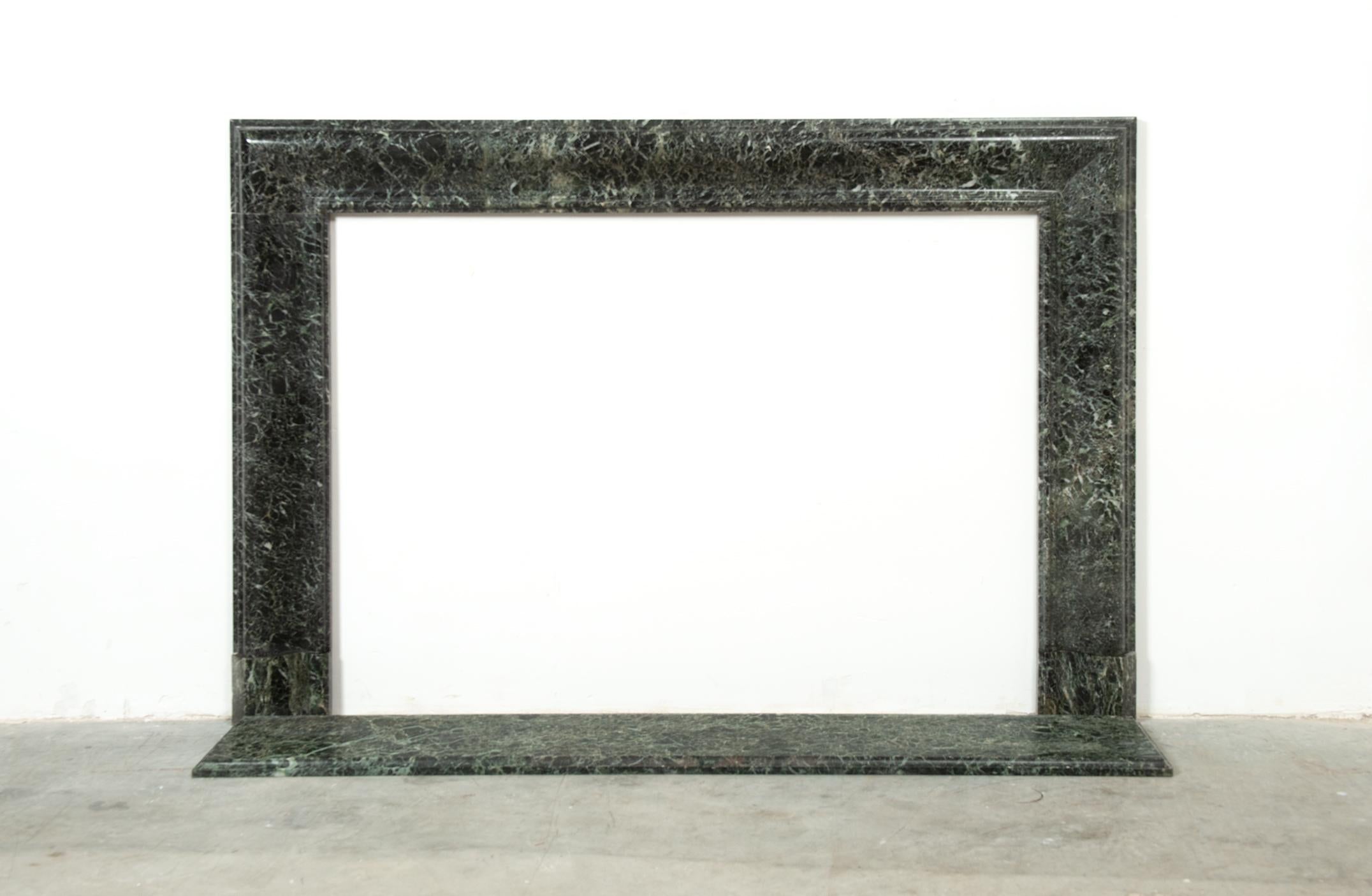 This elegant 19th century French bolection fireplace mantel is crafted from richly veined green marble, displaying a timeless balance of sophistication and understated luxury. The bolection molding, with its smooth rounded profile and clean