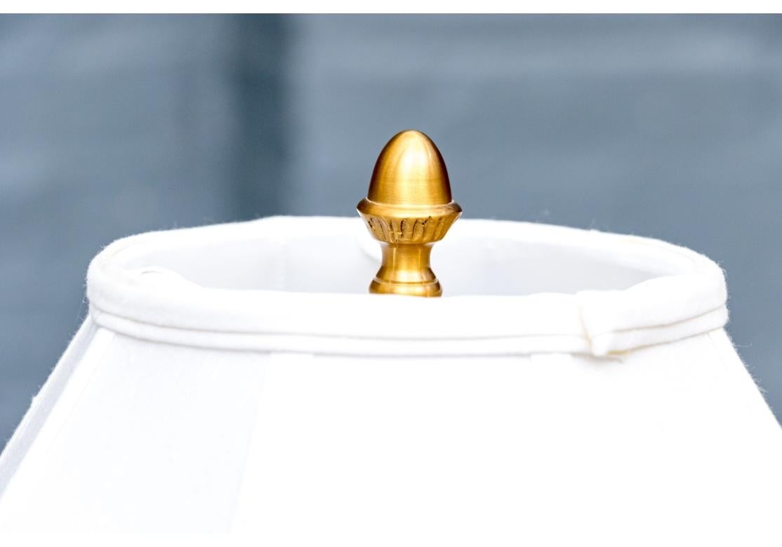 Una straordinaria lampada da terra in marmo verde a forma di colonna corinzia con un capitello ben fuso e accentuato da anelli in ottone. La lampada poggia su una base quadrata a più livelli in ottone dorato ed è coperta da un paralume rivestito in