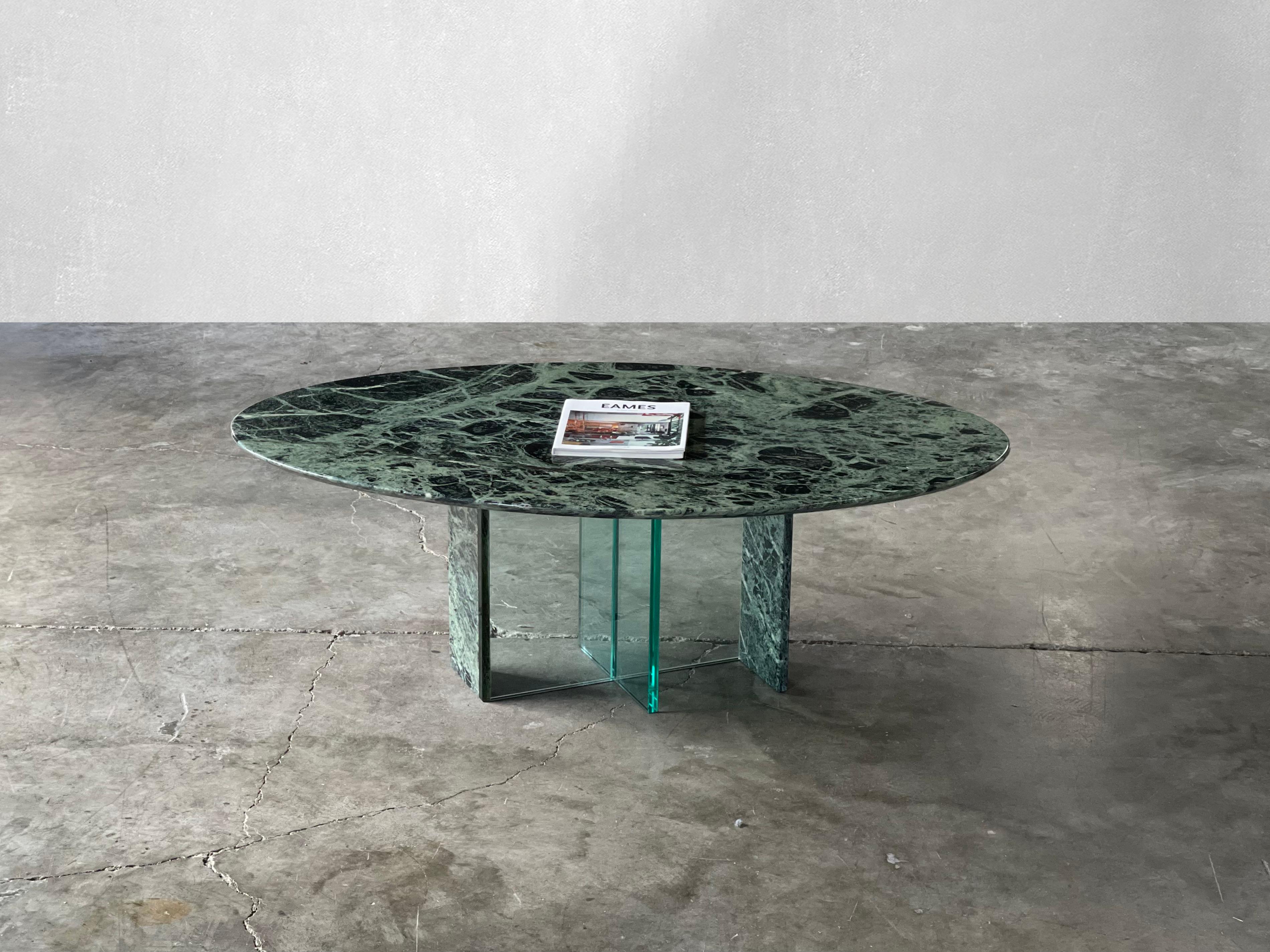 Striking post-modern oval green marble coffee table. This coffee table boasts a matching marble and glass base. The top has mesmerizing natural movement. Love the different shades of green. The top looks as if it is floating on the base.

The