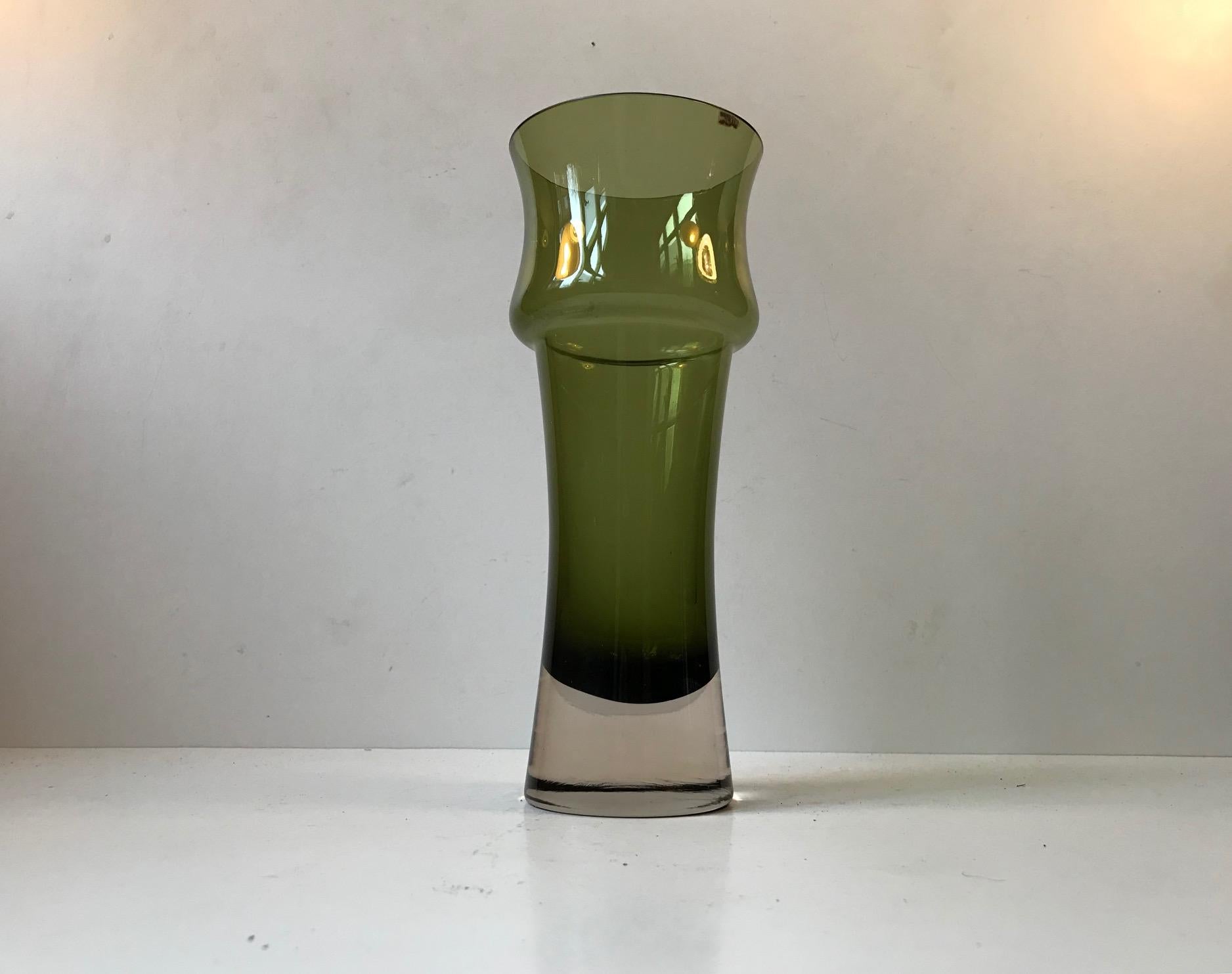 This olive green vase was designed by Tamara Aladin in 1970 and manufactured by Riihimaen Lasi. The vase retains its paper label with the country of origin (Finland).