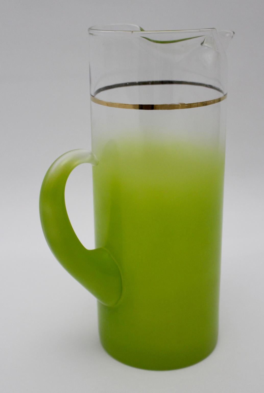 A green charming vintage pitcher, which has a capacity of 2 liters.
The material of this barware is clear glass and the color goes from clear into green, furthermore the glass pitcher is decorated with a fine golden stripe.
The vintage condition is