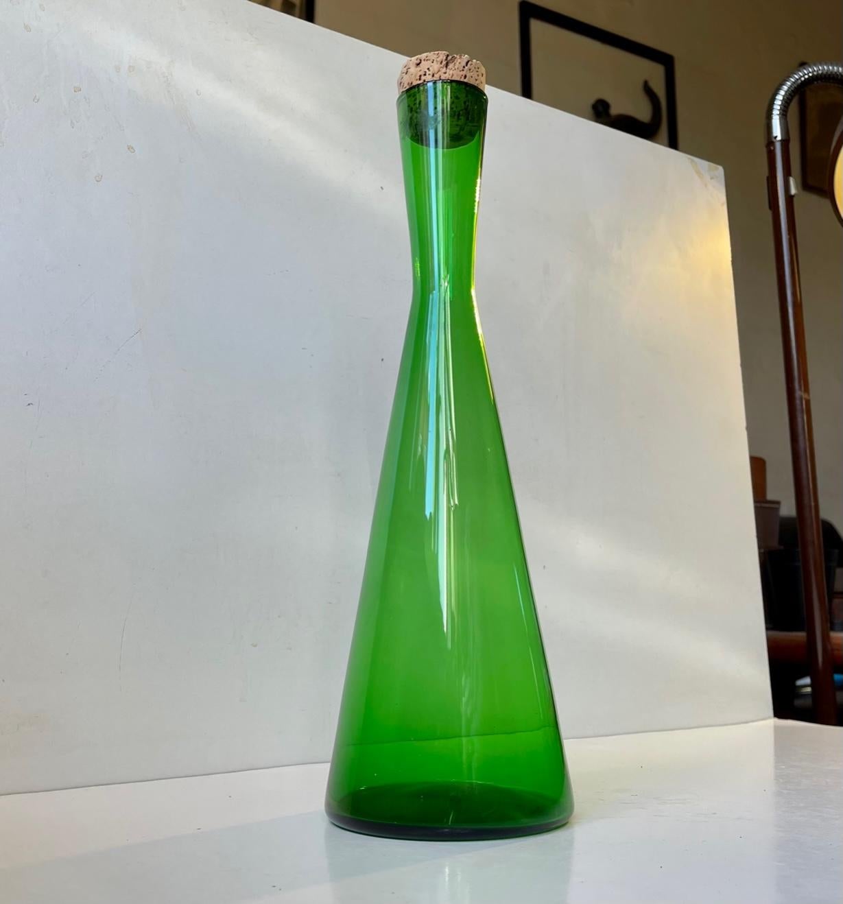 Green hand-blown Winston decanter designed in 1956 by Per Lütken. Manufactured at Holmegaard in Denmark between 1956-65. Its very rare featuring its original cork stopper. Measurements: height: 36.5/34.5 cm, diameter: 11 cm. It can contain approx. 1