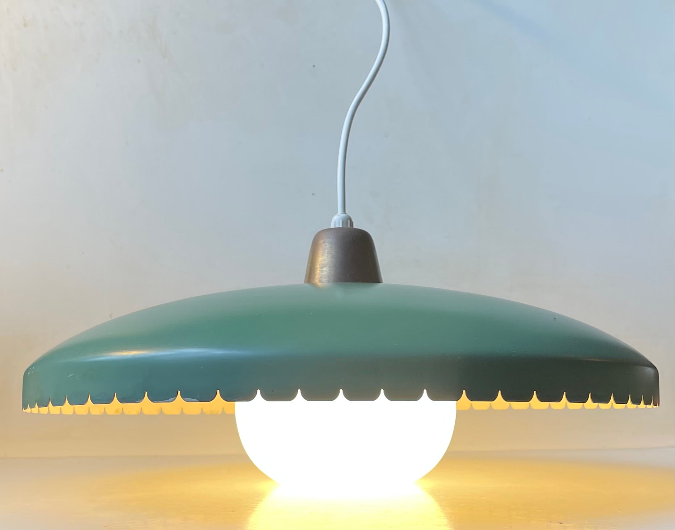 A large Danish ceiling light designed by Bent Karlby for Lyfa, Denmark and manufactured in the late 1950s. The light consists of a green lacquered shade with a wavy bottom edge, a center shade in opaline glass and a top in patinated brass.