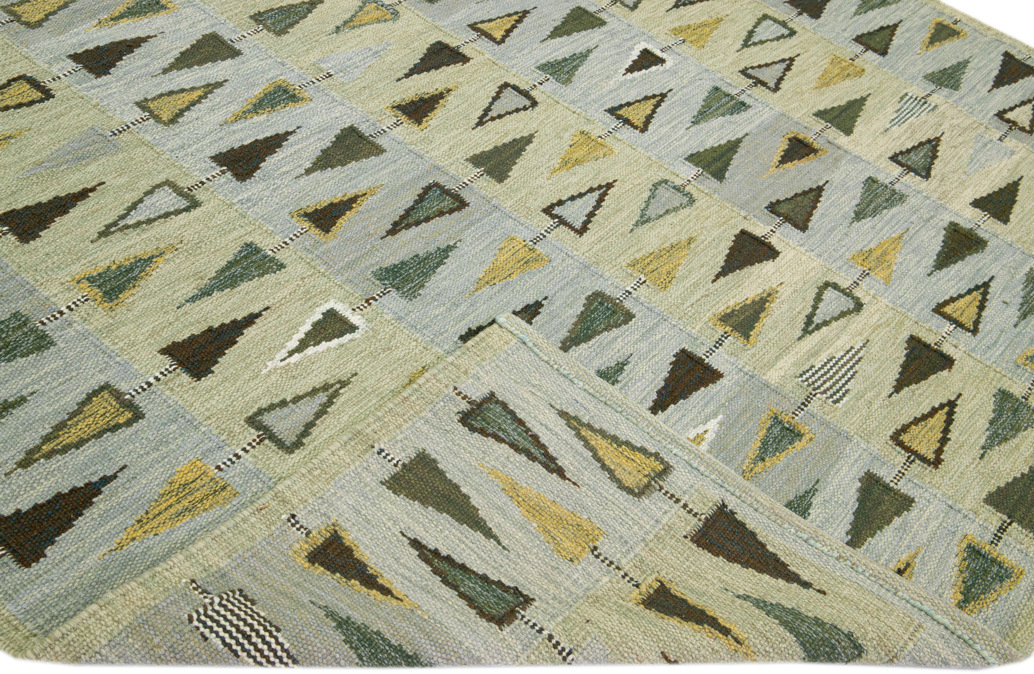 Beautiful Scandinavian style wool rug with a green and grey field. This modern rug has accent colors of yellow and brown in a gorgeous all-over geometric pattern design.

 This rug measures: 9'1