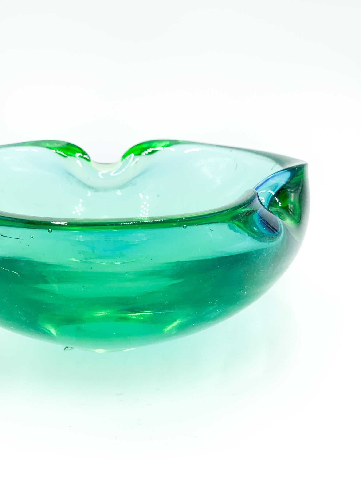 Green and Blue Murano glass ashtray, whose realisation is attributed to Flavio Poli and made in the 1960s

The ashtray has been realised with a particular color infusing technique: green with blu shades according to different perspectives.