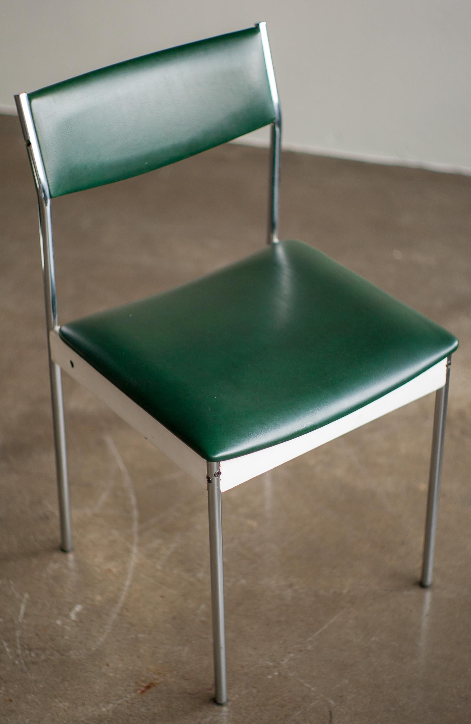 Minimalist but very comfortable Mid-Century Modern matching set of 4 dining chars with chrome plated tubular steel legs and white lacquered plywood seat and back, upholstered in dark green Naugahyde. 
Patent pending stamp, unknown manufacturer and