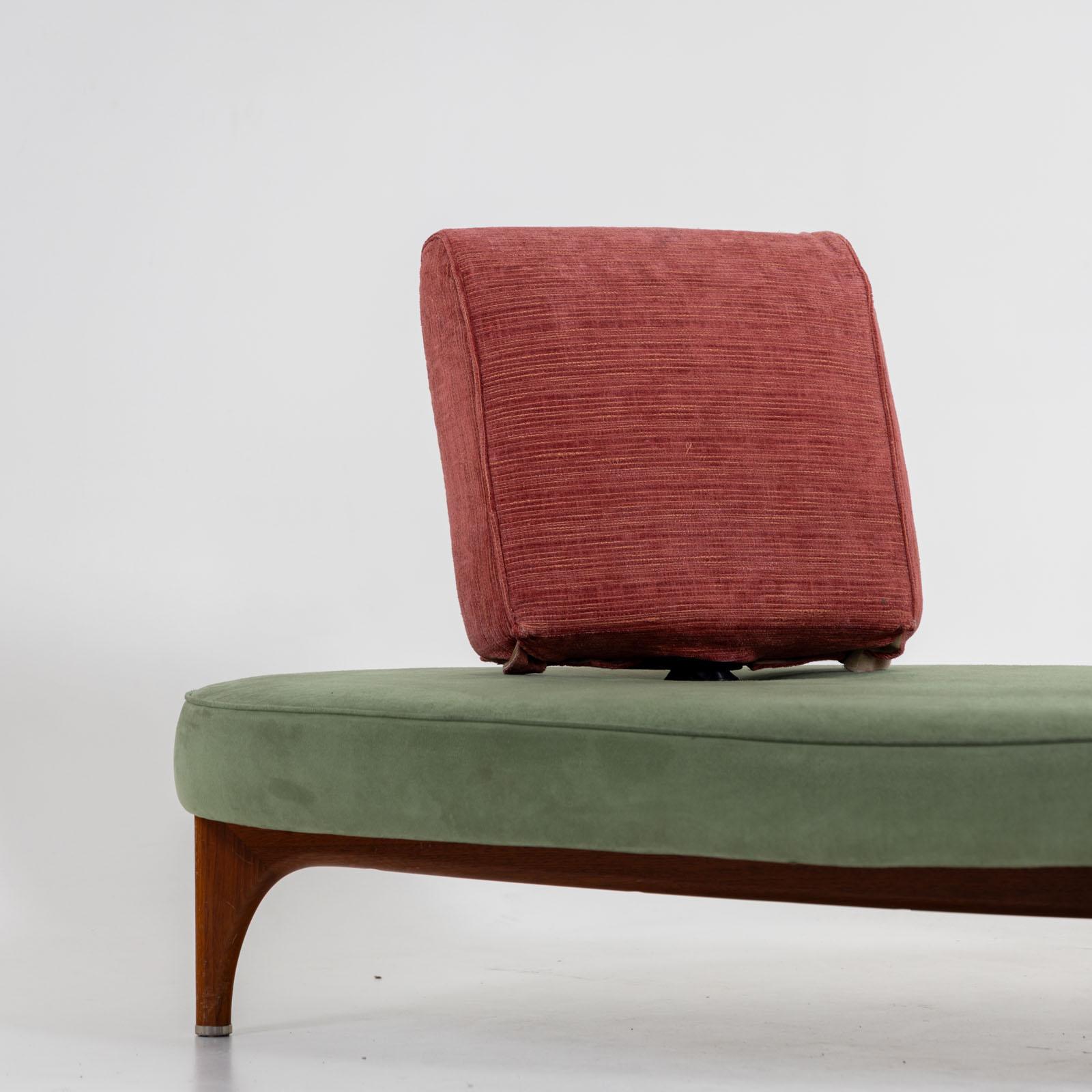 Large sofa with oval seat and rose-colored cushions, which can be turned and bent in any direction. The sofa stands on a smooth wooden base. The upholstery is in good, used condition. The sofa was designed in 1987 by Maarten Kusters (born 1956) for