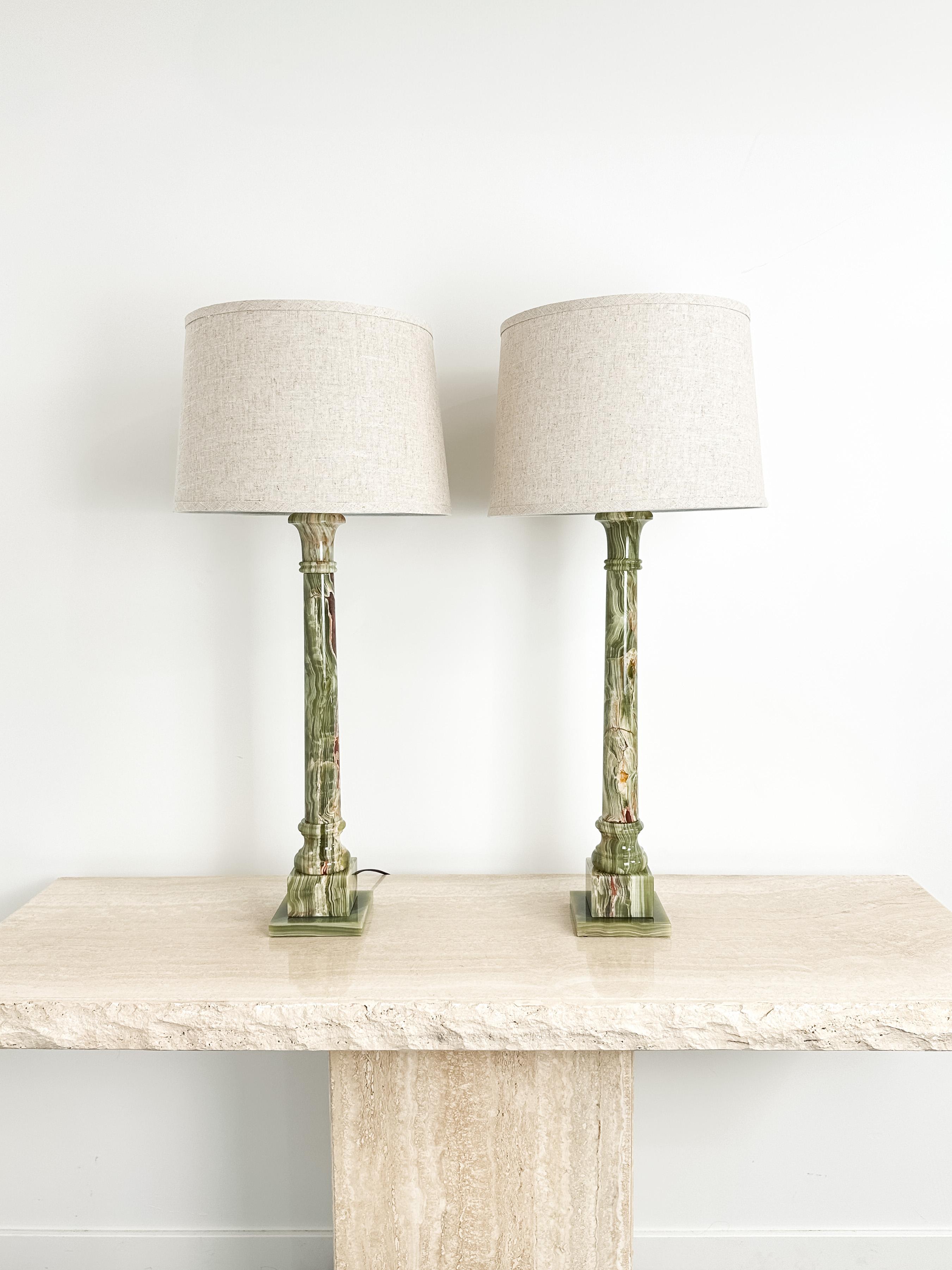 This sculptural pair of 1950s French table lamps brings together classical form and natural materiality. Tall and architectural, their columnar silhouette nods to neoclassical design with echoes of Hollywood Regency and French Art Deco. The result