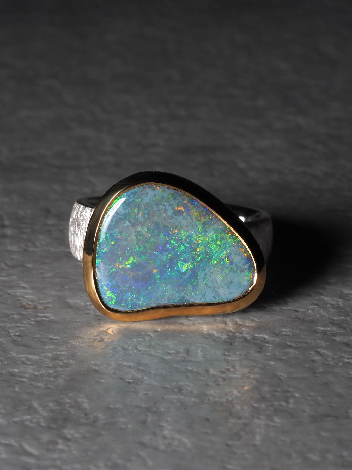 Ein skulpturaler Ring mit einem natürlichen australischen Opal von 0,51 × 0,63 Zoll (13 × 16 mm), der sich durch lebhafte Grün- und Blautöne mit gelegentlichem Aufblitzen von rotem Feuer auszeichnet. Die freie Form des Steins unterstreicht seinen