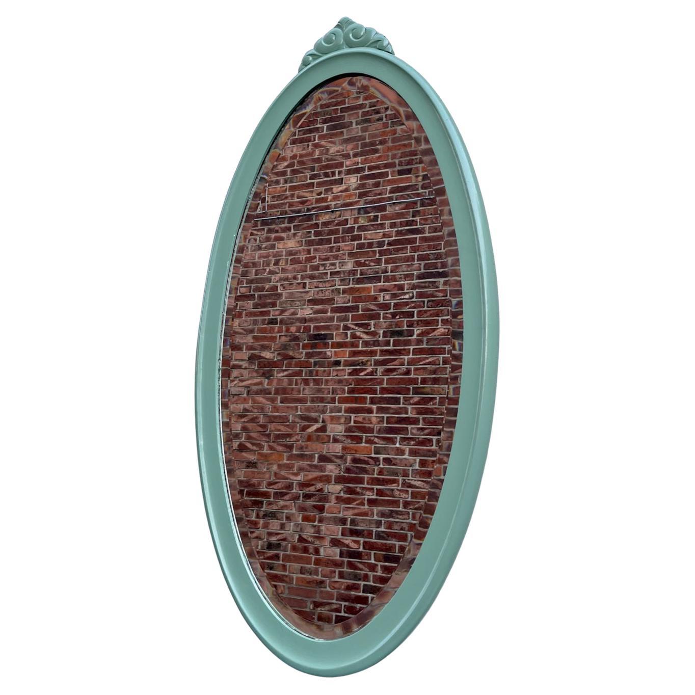 A large 'full figure' (109 cm) mirror in painted pine. It features a beveled mirror glass and rounded profiles that compliments its soft oval shape. It was made by an anonymous cabinet maker in Scandinavia during the 1930s or 40s. The light green