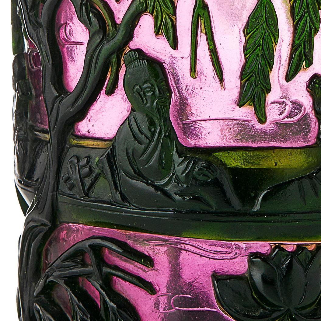 Green-overlay Chinese peking glass brush pot
of cylindrical form, decorated on a purple-tinted ground with two scholars in a boat drifting across a lotus pond below willow trees, apocryphal Qianlong mark to the base.

Measures: 15cm high.