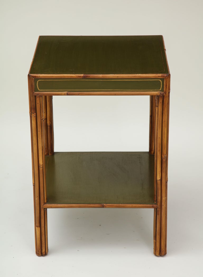 The square top, frieze, and platform stretcher painted a moss green with ochre banding; raised on straight bamboo legs.