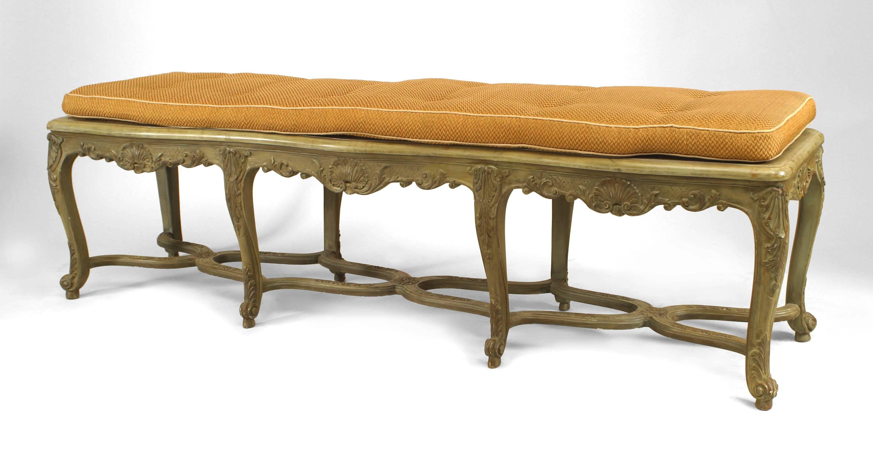 French Regence style (19/20th Century) green painted bench with floral carving and 8 legs connected with a stretcher and shaped cane seat under a cushion.

