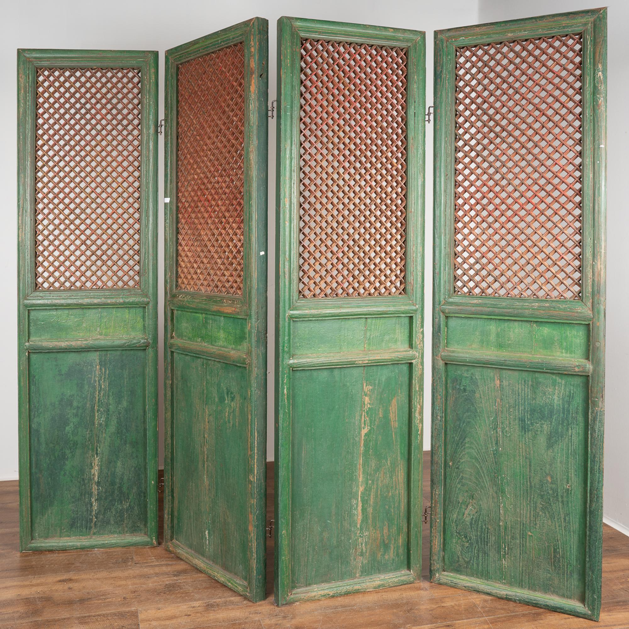 A set of four large carved elm wood interior folding screen panels that still maintain their original green painted finish, topped by traditional Chinese fretwork design left in contrasting natural wood with faint, residual red paint.
Each of the