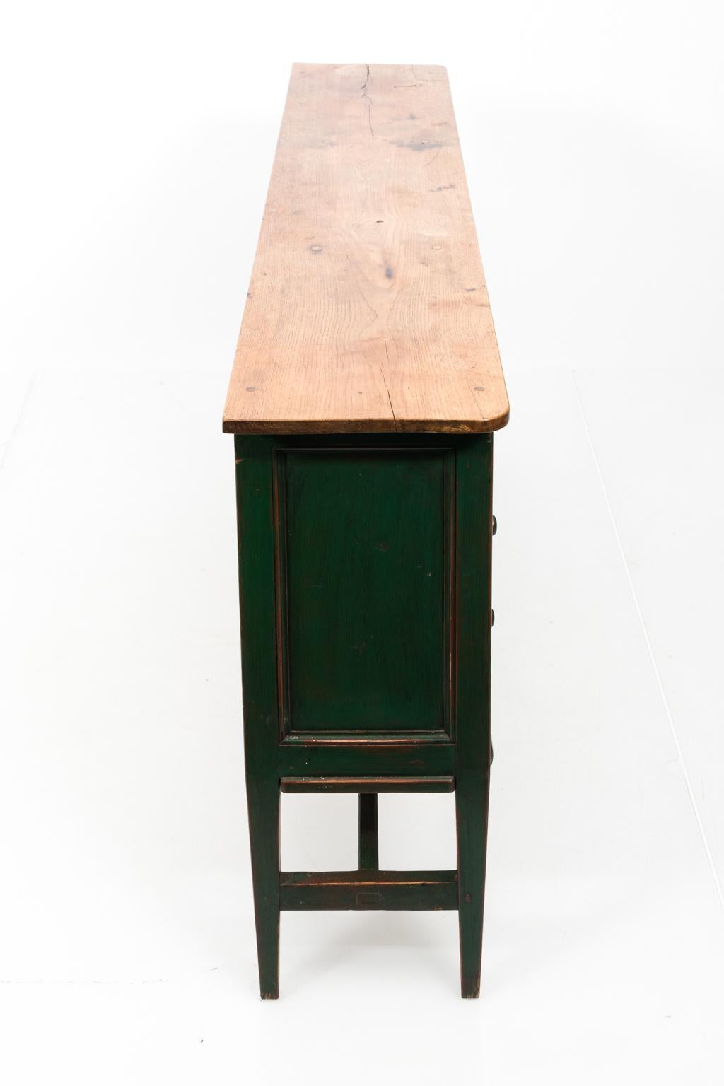 Green painted, custom made sideboard from England with sixteen drawers, oakwood top, and long H-shaped cross stretcher, circa 1990s. Please note that the Oak tabletop has a split in the wood on the right most edge.