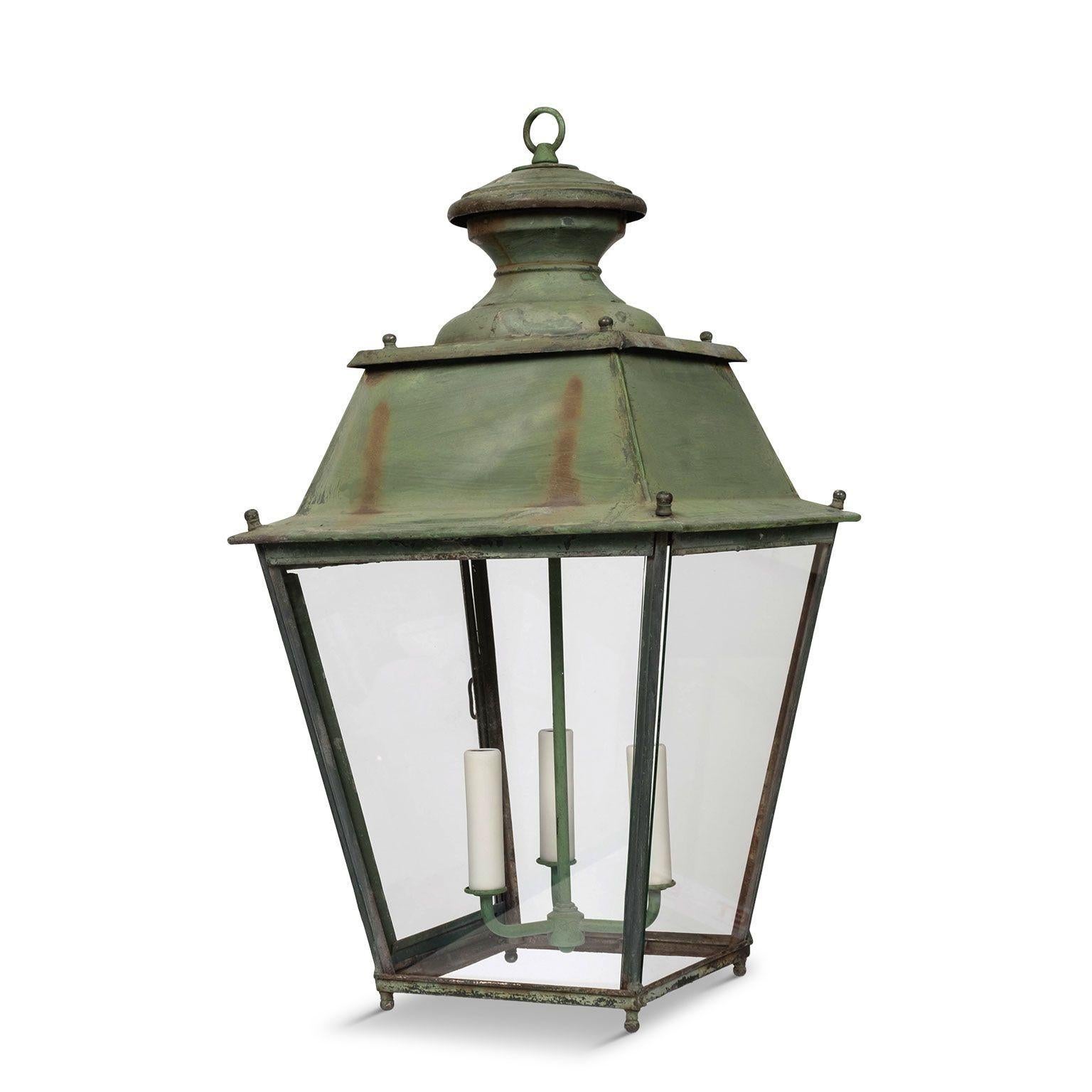Lanterne en fer à panneaux de verre peints en vert, vers 1900-1930. Nouvellement câblé avec une grappe de trois lampes candélabres. Comprend une chaîne et un baldaquin (les mesures indiquées ne comprennent pas la chaîne).