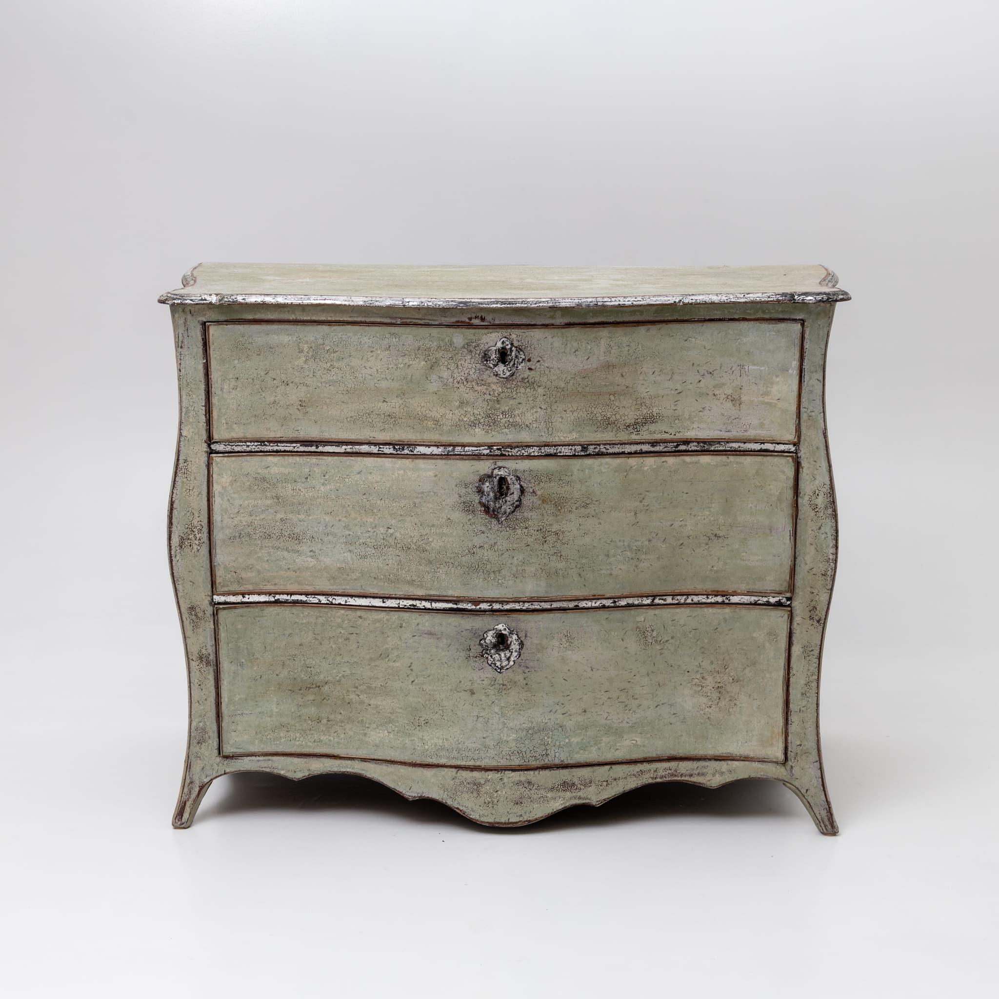 Commode Louis XV peinte en vert avec trois tiroirs et une garniture argentée le long des rails et du bord du plateau. La façade légèrement incurvée est complétée par un tablier serpentin. La peinture est neuve et a été patinée à l'ancienne.