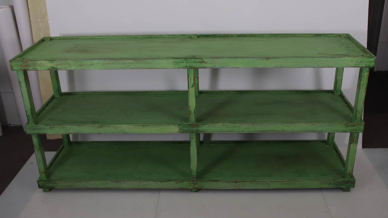 Green painted two-tier pottery table with three shelves. Please note of wear consistent with age including chips and paint loss throughout due to daily use.