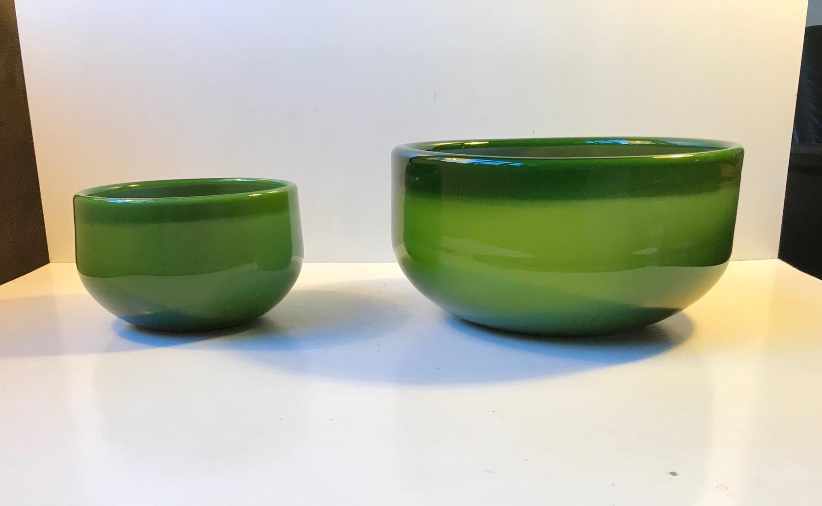 A matching set of Palet bowls in cased green Opaline glass. Designed by Michael Bang for Holmegaard, circa 1970. The set are hand blown and features the characteristic folded collars.