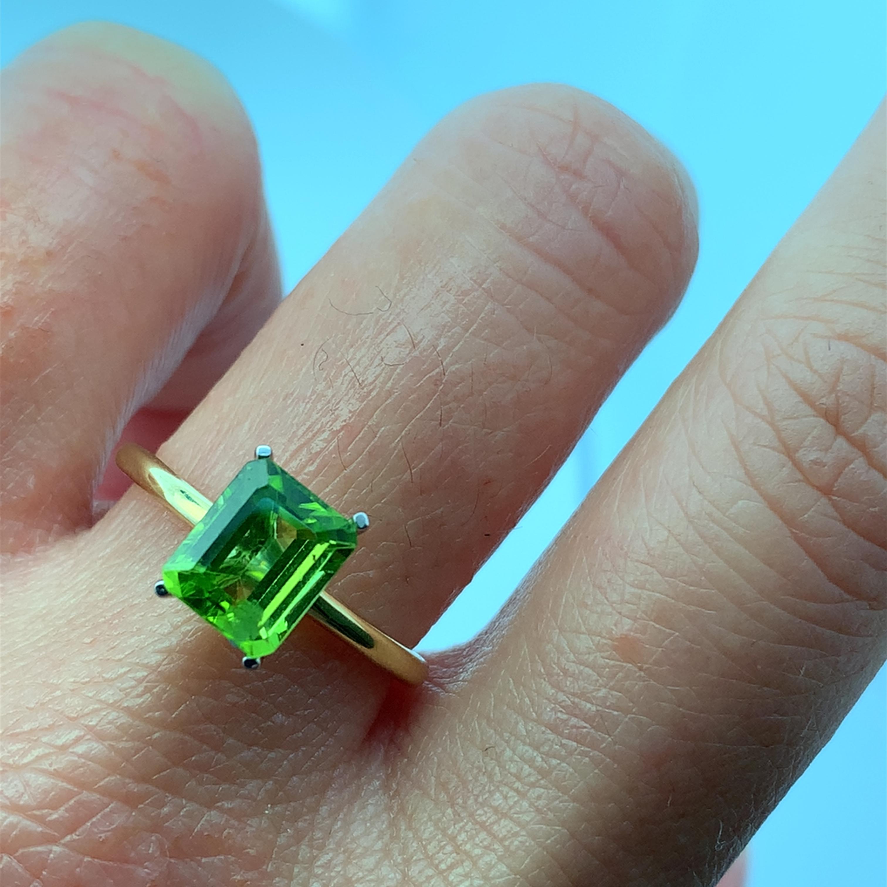 Discover the beauty of this elegant green peridot emerald cut 1.90ct gemstone ring, featuring a stunning peridot emerald-cut stone that captures the light beautifully. The delicate 18k yellow gold band adds a touch of sophistication, making it