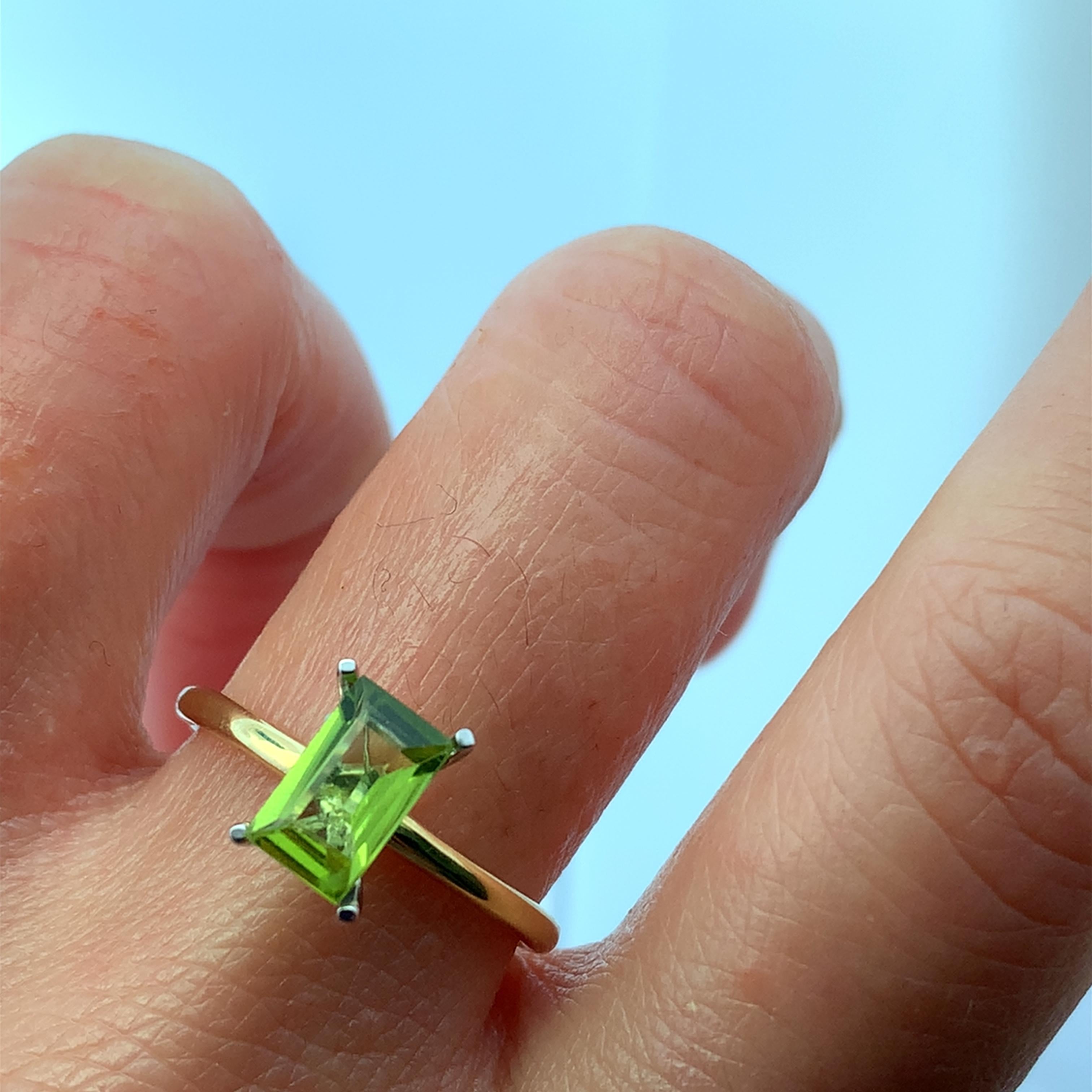This stunning ring features a vibrant green peridot gemstone emerald cut 1.25ct set in a sleek 18k yellow gold band. Its unique rectangular cut catches the light beautifully, making it a perfect statement piece for any occasion. Perfect cocktail