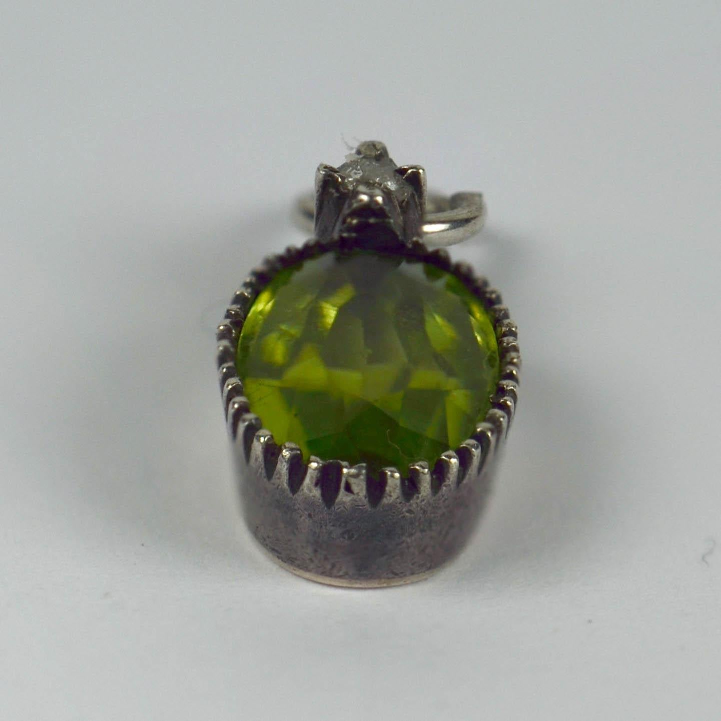 A silver charm pendant mounted with an oval-cut green peridot topped with a rose cut white diamond. 

The peridot measures 9.5 x 5.9 x 3.12mm and has an approximate weight of 1.17 carats.
The diamond measures 2mm in diameter and has an approximate