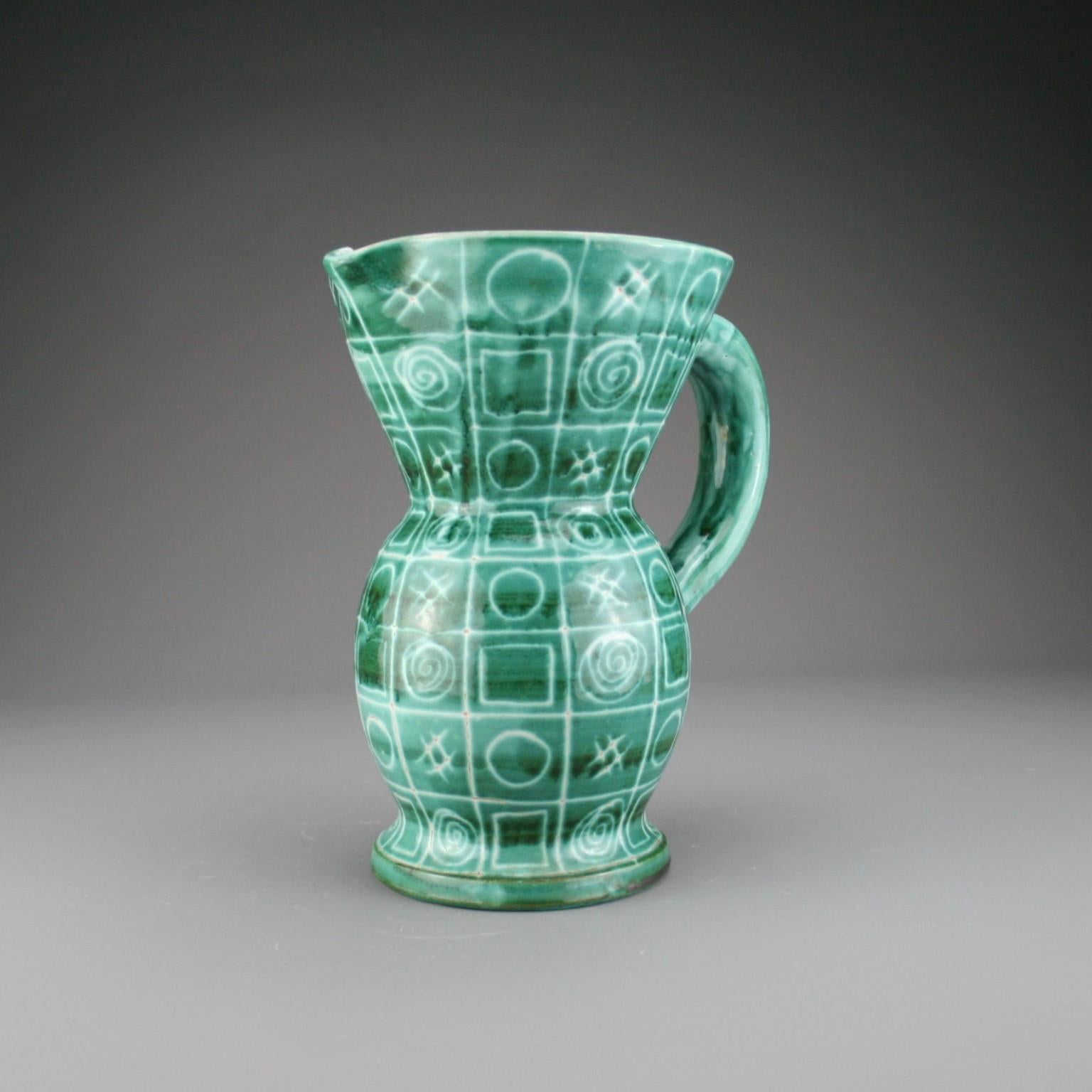 A large pitcher by Robert Picault and made in Vallauris in the South of France. The pitcher is hand decorated with a green glaze and white repeating patterned abstract design.

It has the painted initials RP to the unglazed base.

Robert Picault