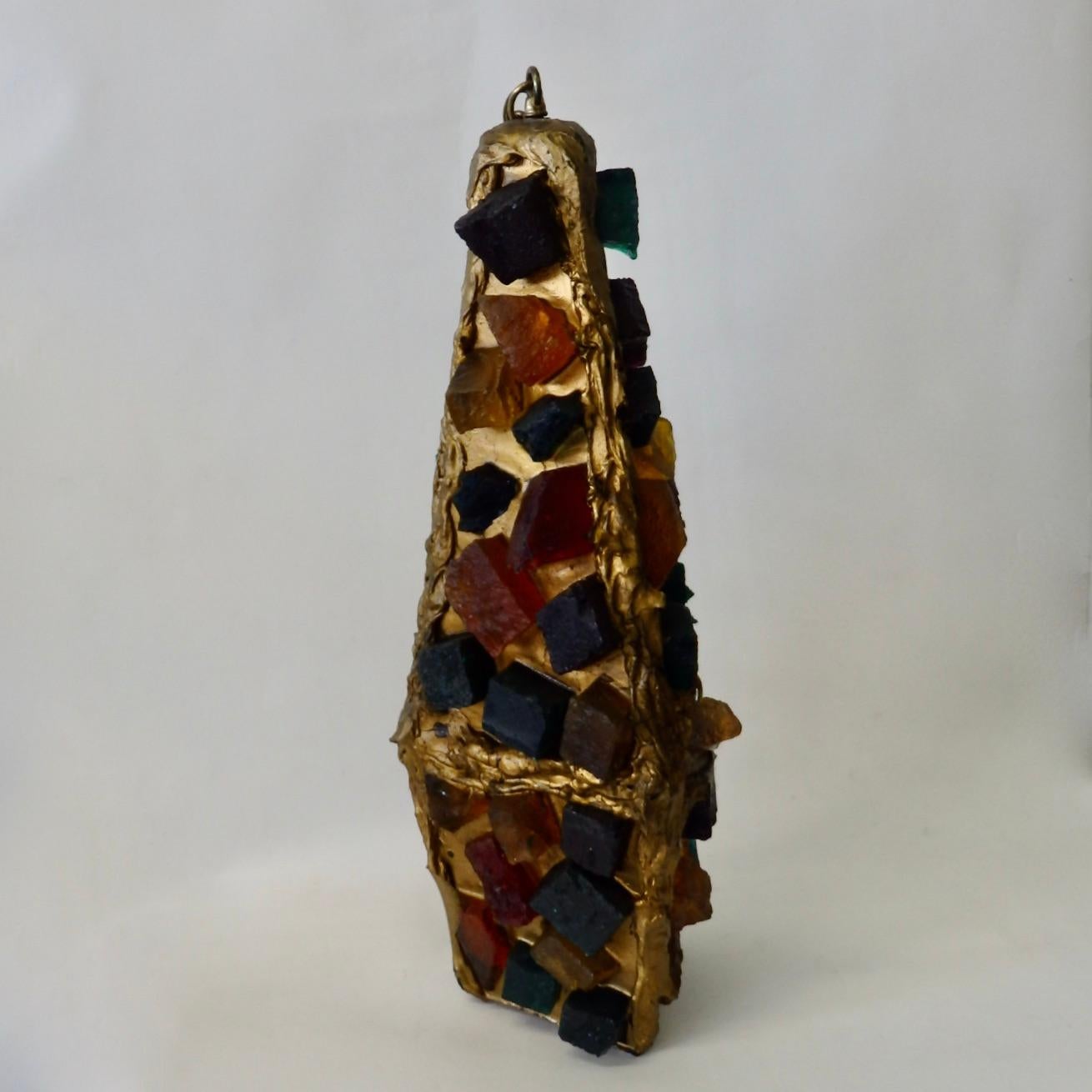 Brutalist hanging lamp of multicolored plastic chunks set in gold tone resin.