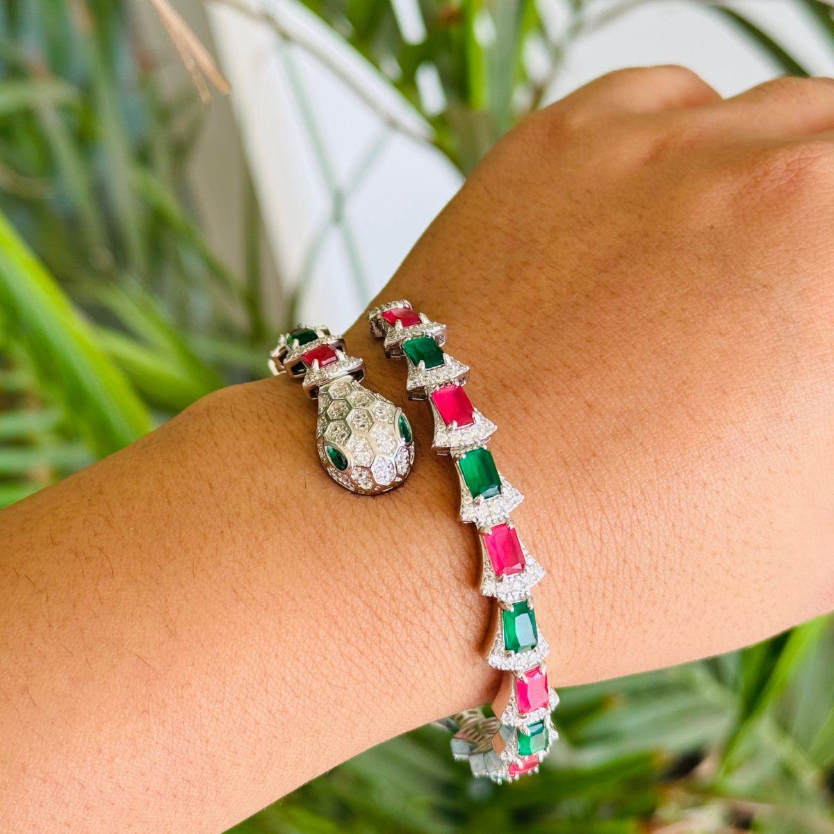 Bracelet manchette serpent en pierres vertes et rouges En argent 925, ce superbe bracelet présente une combinaison captivante de pierres vertes et rouges vives, chacune sertie entre d'éblouissants strass en zircone cubique pour un éclat luxueux. Le