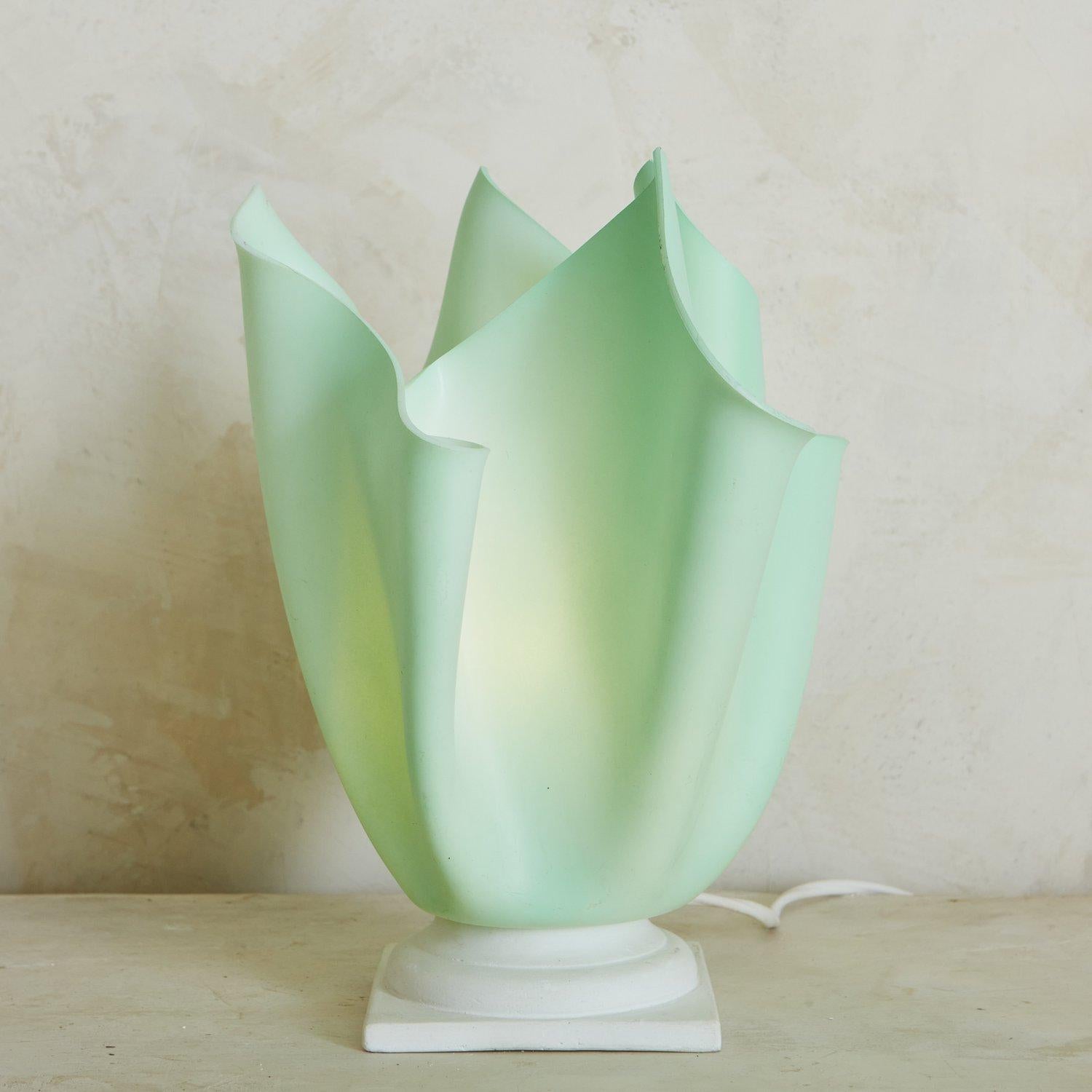 An undulating resin handkerchief table lamp in light green with a white square base. When lit, this sweet accent lamp emits a warm glow. Sourced in Italy, 1970s.

 