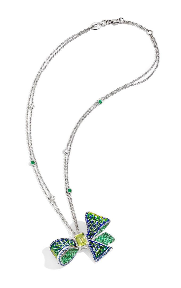 A green ribbon where micromosaic tiles are used as a special yarn to create a spectacular three-dimensional effect. The central peridot gives it additional shine.

White gold 18K, White diamonds 0.31ct, Blue sapphires 1.39ct, Peridot 1.56ct,