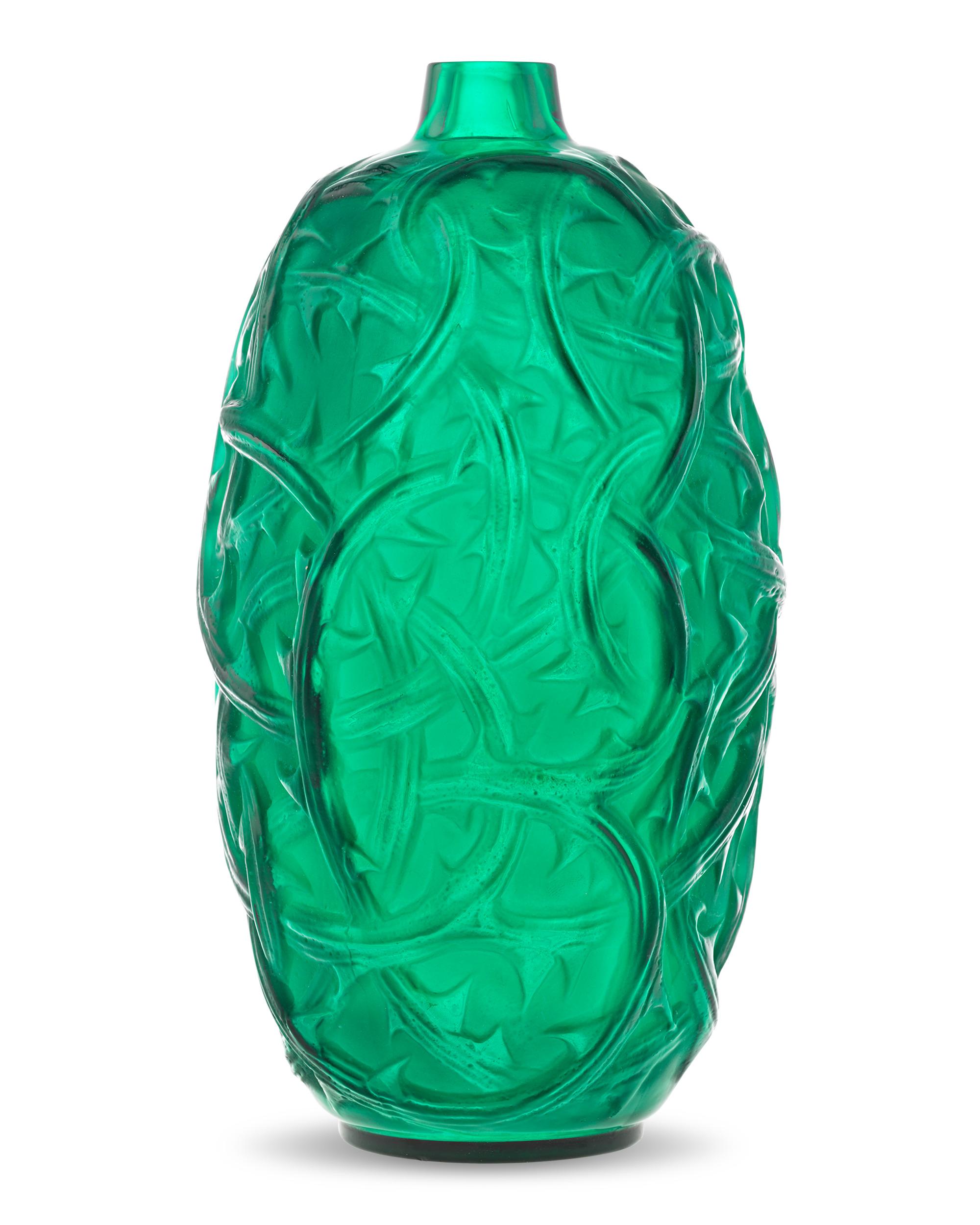 Designed by René Lalique in 1921, this Ronces pattern vase features a bold array of winding blackberry vines. The vessel highlights the master's love of the striking forms and natural motifs that typified his output. Composed of frosted green glass,