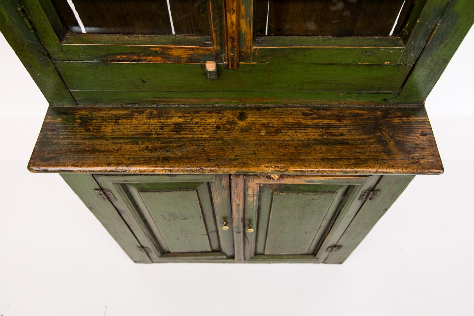 Green Russian cupboard has its original paint. There are raised panel doors on the bottom half and double glass doors
on the top with wavy glass panes.
  