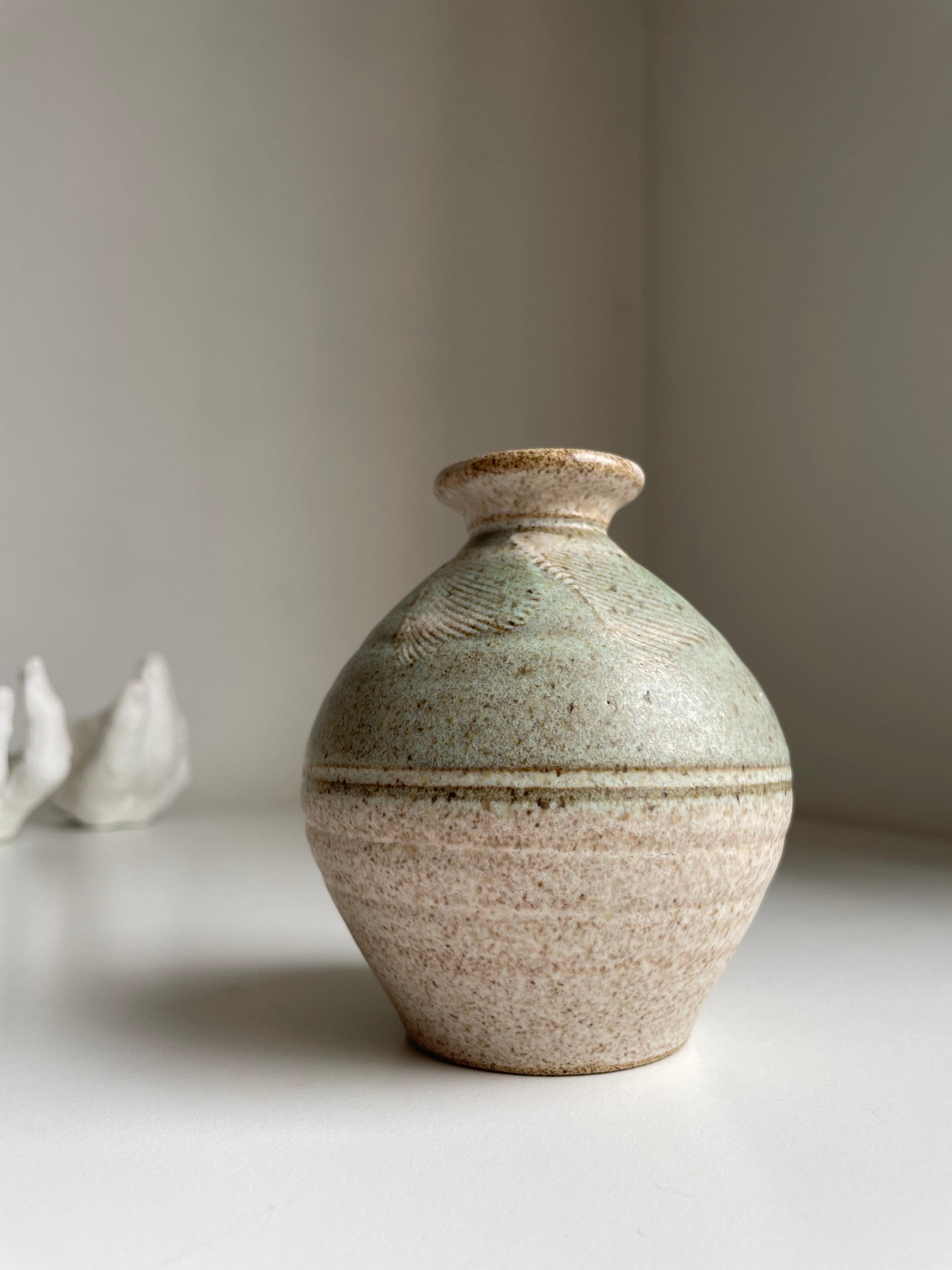Vase vintage en céramique fait à la main avec une glaçure mate vert clair et transparente sur de l'argile de couleur sable. Motifs en relief sur la partie supérieure. Signé sous la base. 
Belle condition vintage. 
Danemark, années 1990. 