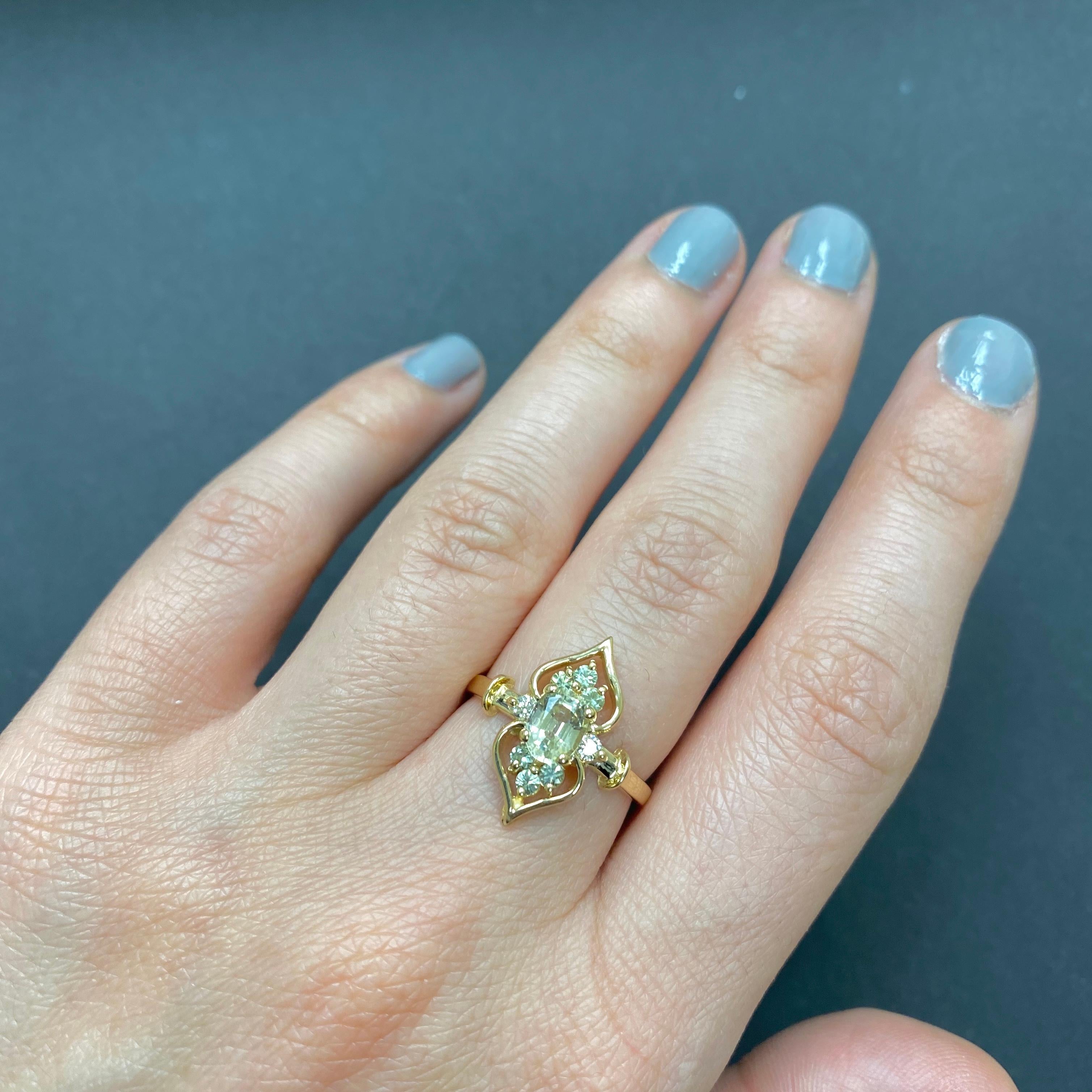 Material: 14k Yellow Gold 
Center Stone Details: 1 Oval Shaped Green Sapphire at 0.77 Carats- Measuring 4 x 6 mm
Mounting Stone Details: 6 Round Green Sapphires at 0.25 Carats
Diamond Details: 2 Brilliant Round White Diamonds at 0.07 Carats -