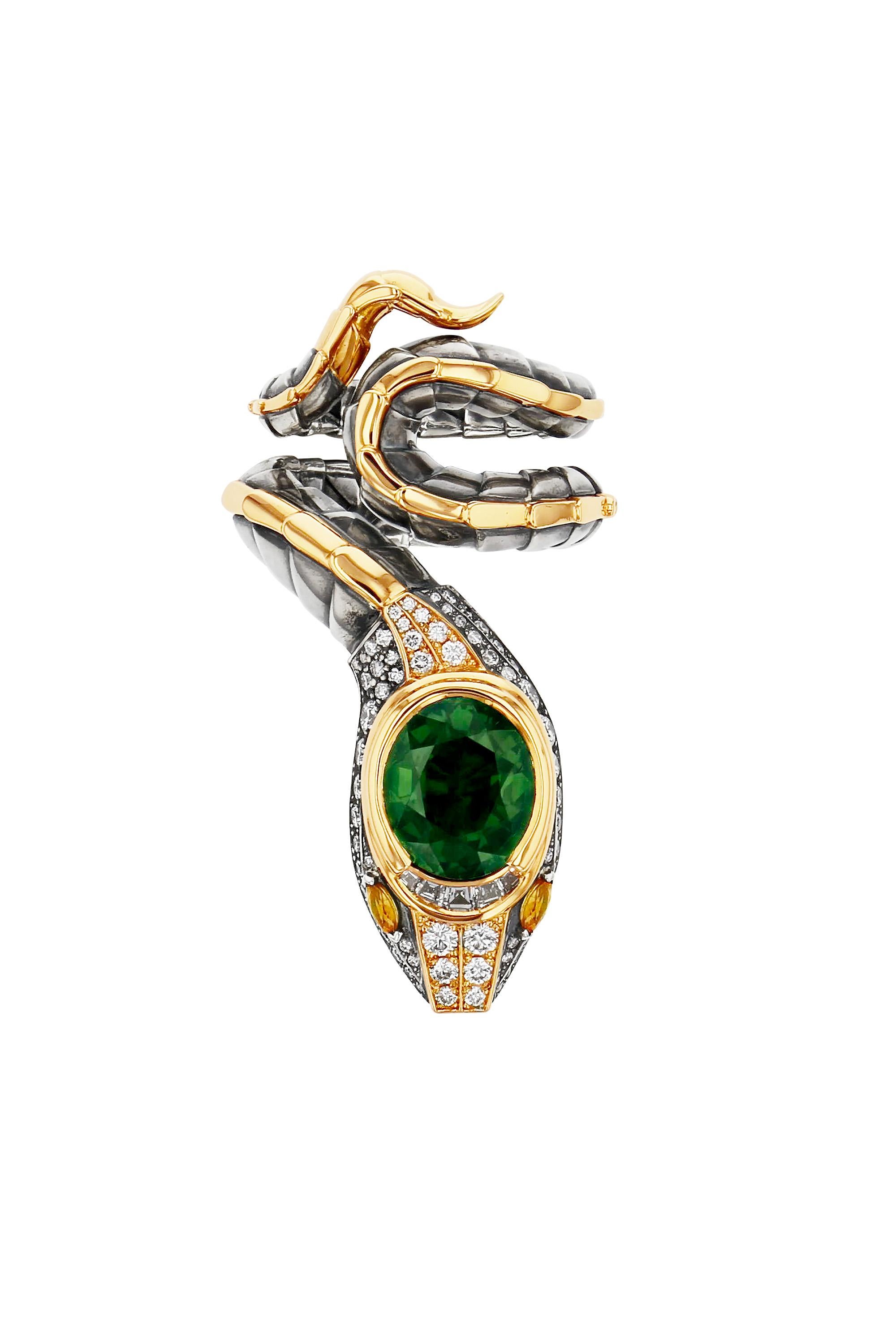 Yellow gold and distressed silver ring. The body, wrapped in distressed silver scales with a yellow gold dorsal ridge, ends with a head that is paved with diamonds and animated with yellow sapphire eyes. At its summit, it is set with a green
