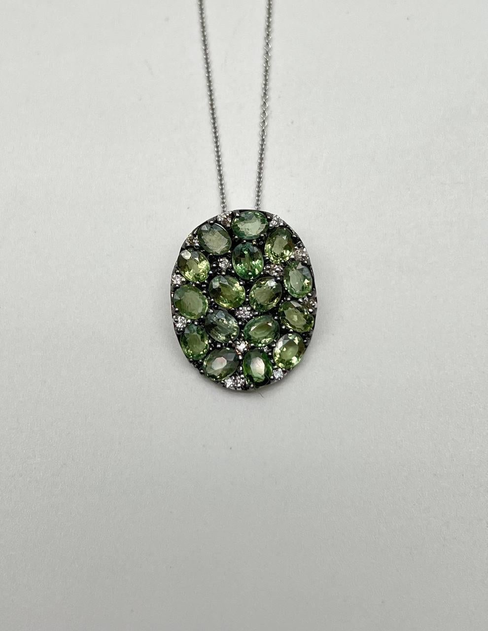 A captivating pendant necklace featuring an array of green sapphires and white diamonds set in an elegant design. 14K White Gold. 4.56 CTW Green Sapphires. 0.15 CTW Diamonds.