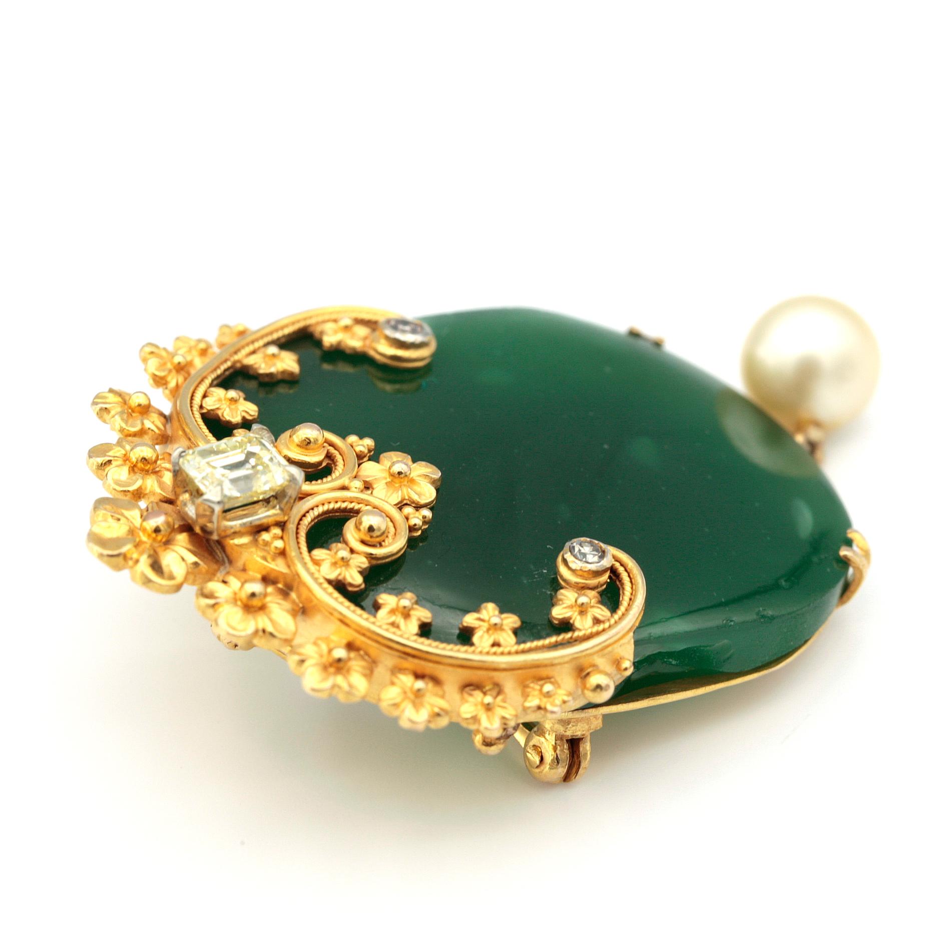 Majestic brooch with a semi-precious green gemstone, set in 10 karat yellow gold frame.
Set on the gold frame, 0.50 carat yellow emerald cut diamond and two round diamonds 0.07 carat each.
dangling from the brooch is a white pearl.
23.54 grams
4.3cm