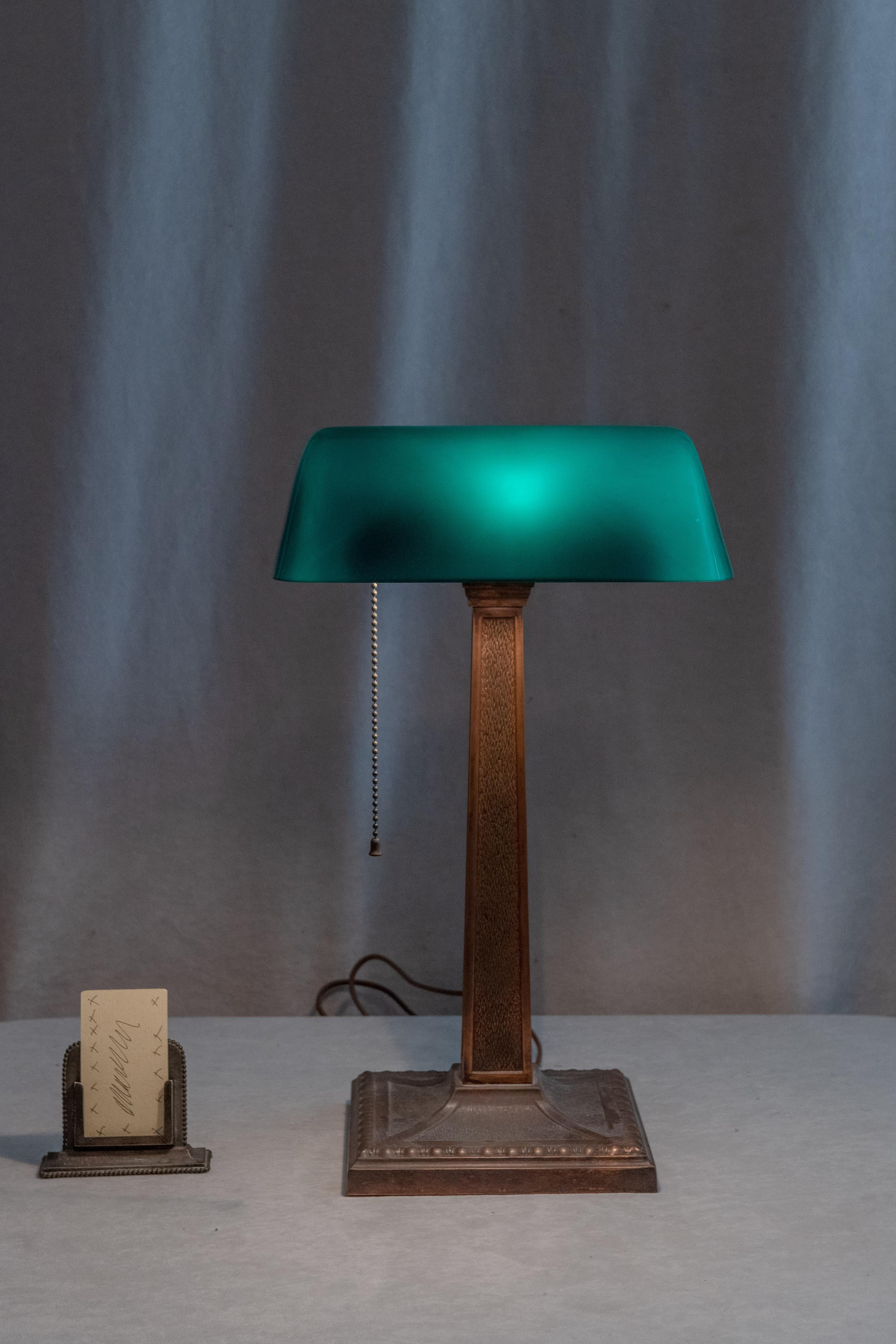  These antique green shaded banker's lamps are some of the most popular and desirable desk lamps. Several companies produced these lamps that were originally designed by H.D. McFaddin in 1909. 
  This example has one adjustment for the angle of the