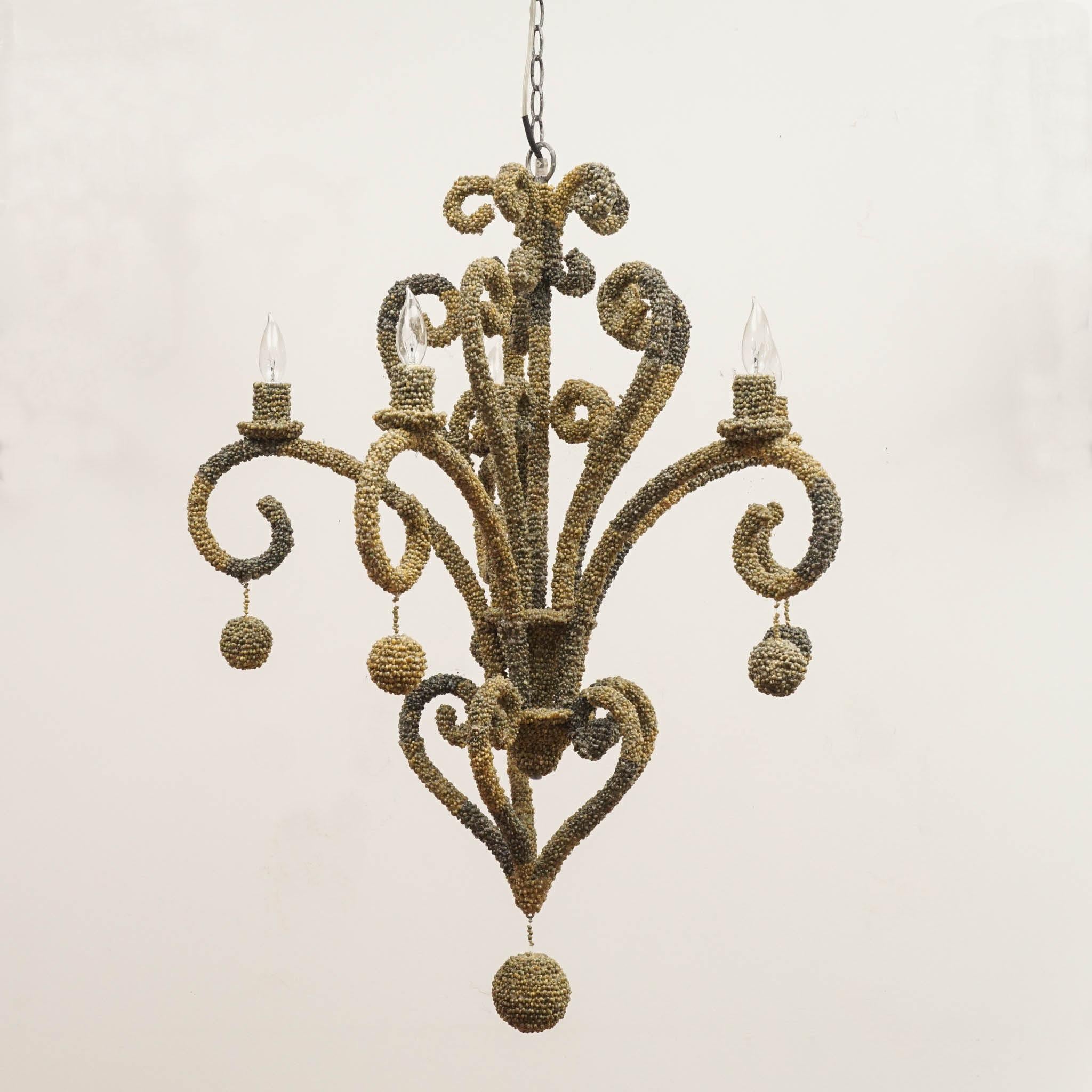 Intricately put tiny sea shells cover this elegant chandelier. Hand-applied all over the fixture, the detail makes this art in itself. Five lights are on curved arms, and each arm has a shell covered decorative ball hanging from it, plus a final one