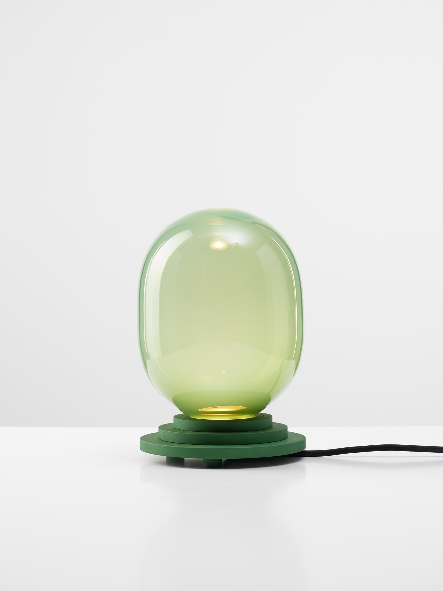 Green stratos capsule table light by Dechem Studio
Dimensions: D 15 x H 22 cm
Materials: Aluminum, glass.
Also available: Different colours available.

Different shapes of capsules and spheres contrast with anodized alloy fixtures, creating a