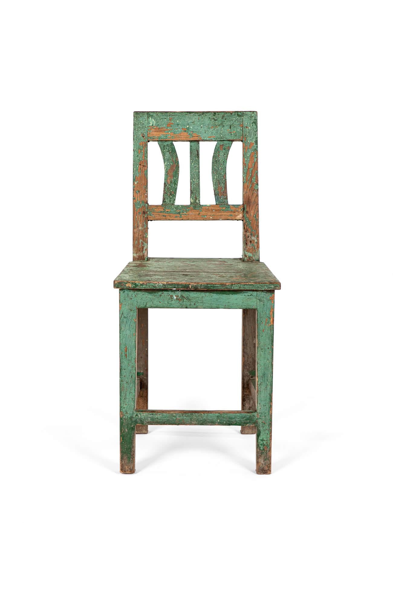 Una sencilla silla auxiliar escandinava de pino con acabado de pintura verde oliva.

El respaldo con listones curvos decorativos y un respaldo recto con un asiento de dos tablones desgastado por el tiempo .

La pintura está desgastada y desconchada