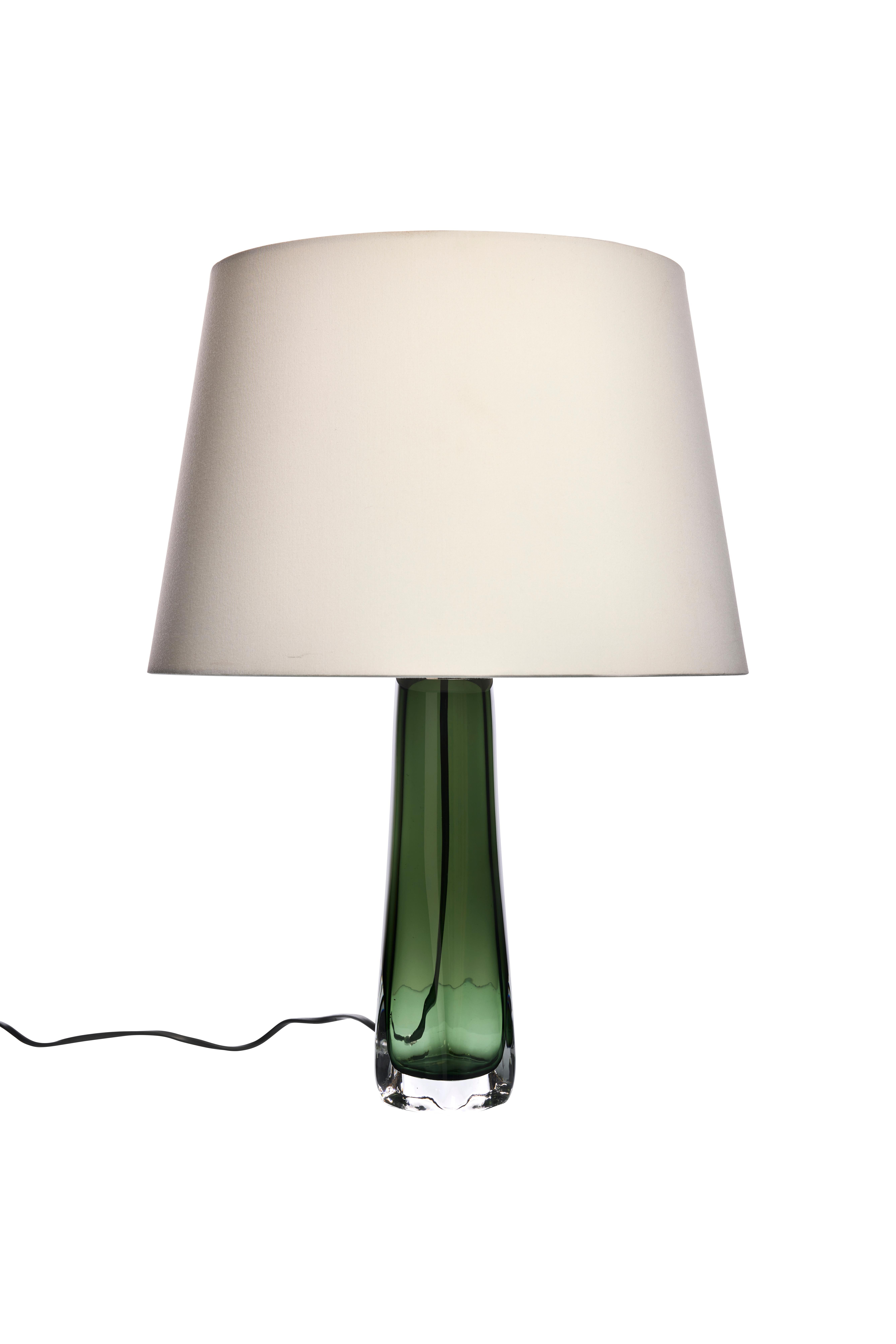 Cette lampe de table, conçue par Carl Fagerlund pour Orrefors dans les années 1960, est dotée d'une étonnante base en verre vert. La forme élégante et allongée de la base met en valeur le travail artisanal de haute qualité du verre Orrefors,