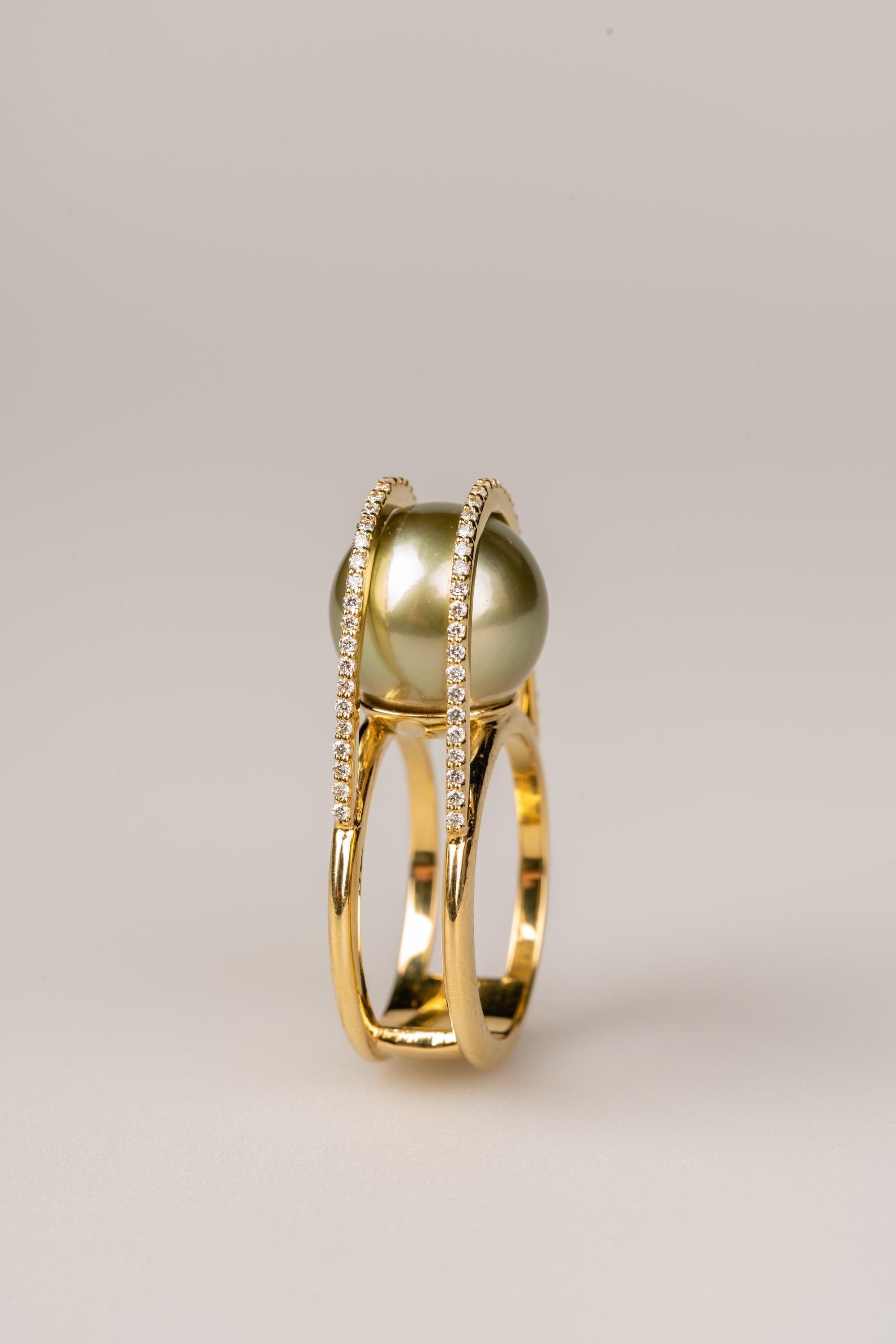 Une bague en or jaune 18k sertie d'une perle de Tahiti verte de 12,5 mm, et de deux bracelets de soixante-quatorze diamants bruns clairs de 1,0 mm, d'un poids total de 0,37 carat. Bague taille 6.5. Cette bague a été fabriquée et conçue par llyn