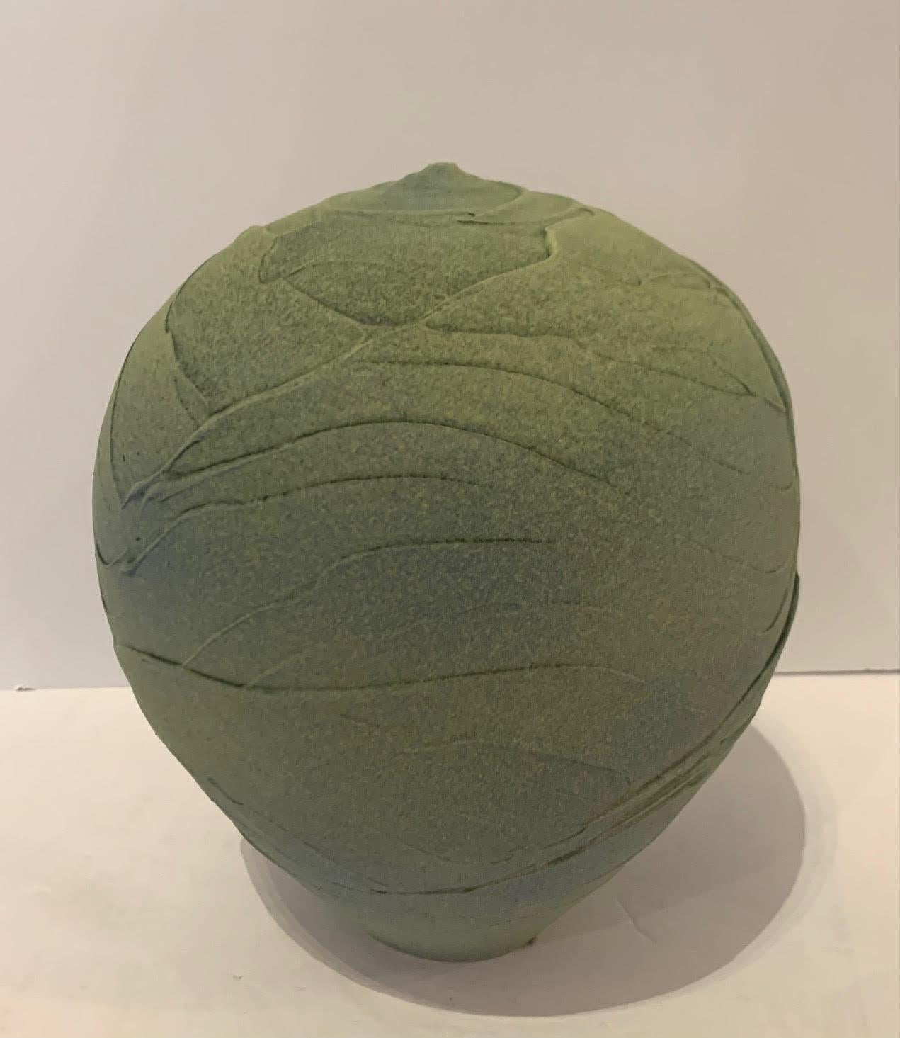 Contemporary textured round ceramic earthenware vase.
Classic shaped textural round green body. A swirled band of muted blue is subtly air brushed at the center of the vase.
The vase design has an ancient feel.
Hand made one of a kind.
Part of a