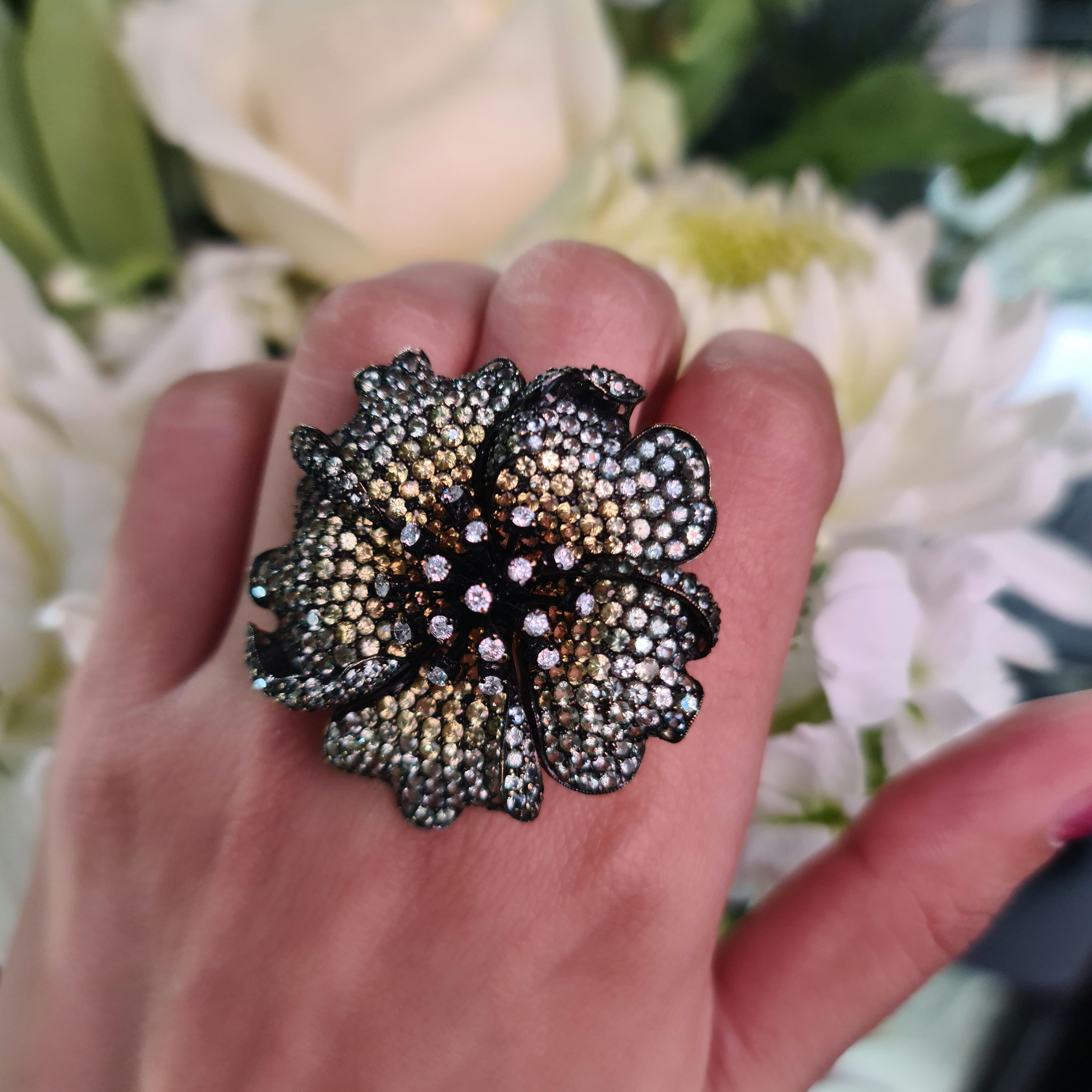 A modern shaded sapphire rose ring, with pavé set green and yellow sapphires, in the curving petals, shading lighter towards the centre, with a total weight of 12.70ct and round brilliant-cut diamond set stamens, in claw settings, with a total