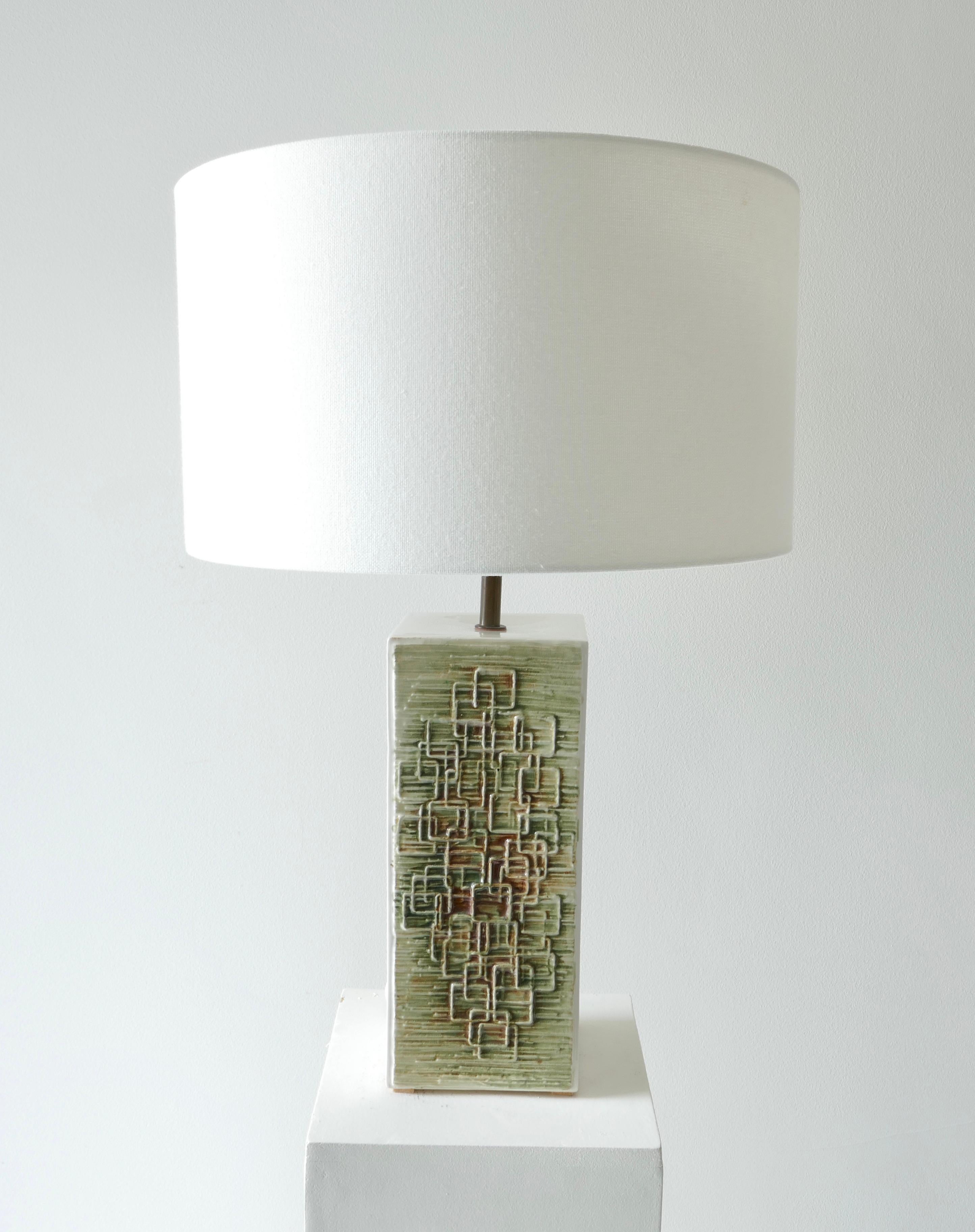 1970s German ceramic lamp
Off white base with 2 sides with geometric relief over a a green background with touch of brown in cubist style.

Measures: Lamp base 10 x 10 x H27cm with lampshade the overall height is 57cm.

 