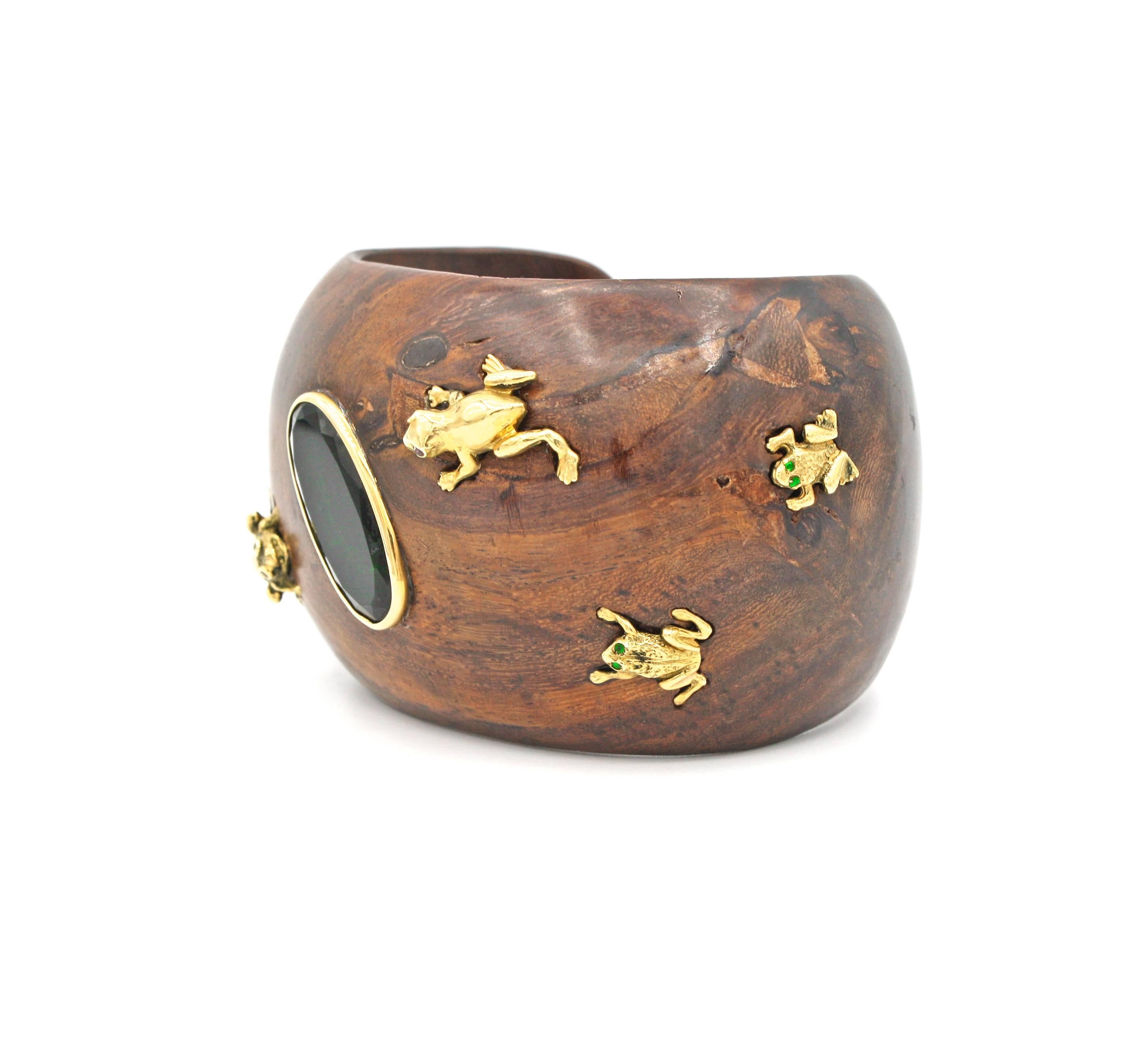 Rich cuff Bracelet of Yellow wood set with a oval cut green topaz and various 18k gold frogs and ladybug which have details of emeralds, rubies and black diamonds.  All the gold elements and stone are set into the wood, giving the cuff