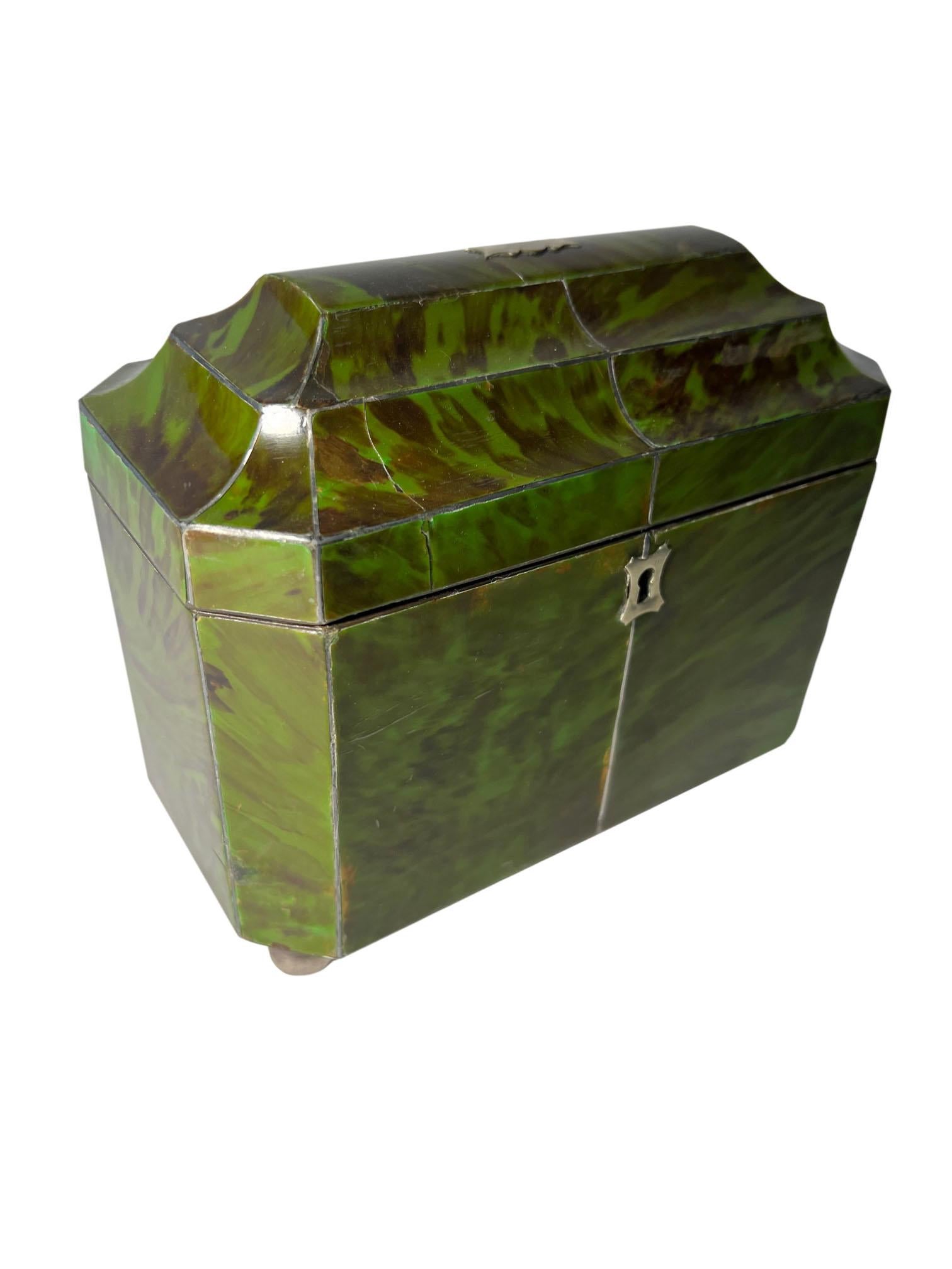 Green tortoiseshell tea caddy from England. With two interior covers raised on four silver ball feet. Circa 1870.