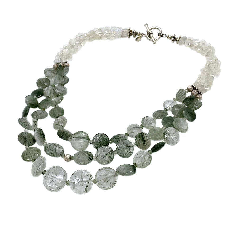 This green tourmalinated quartz  triple strand necklace is an original work of Nouveau Boutique. We created this princess length necklace with up to 10 mm faceted green tourmalinated quartz button beads and 8 mm white chalcedony coin beads. It has a